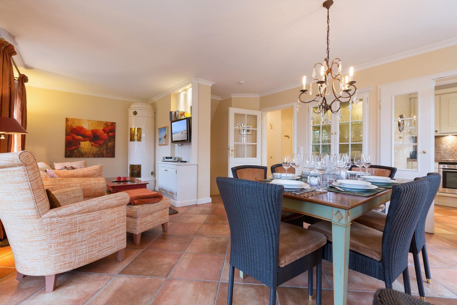 Dining area with table and chairs, living area with sofa and TV, terrace and kitchen visible.