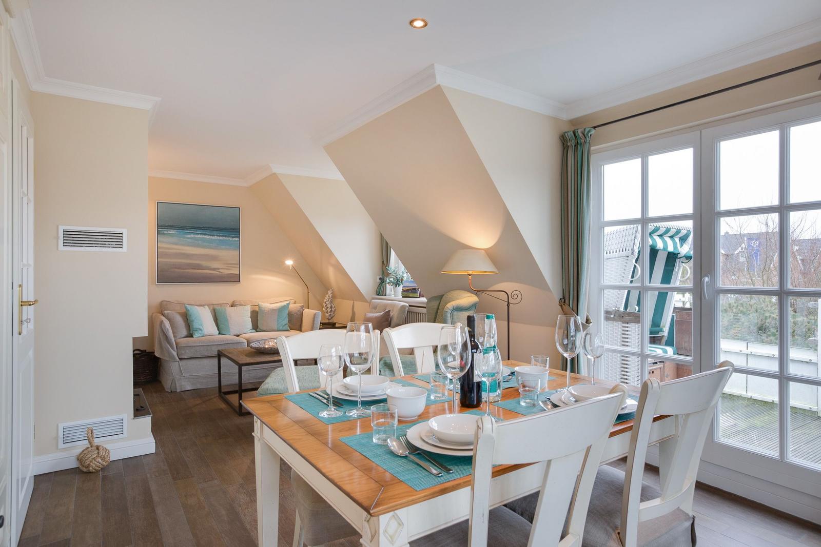 Dining area with table and chairs. Passage to living room with sofa and wall art.