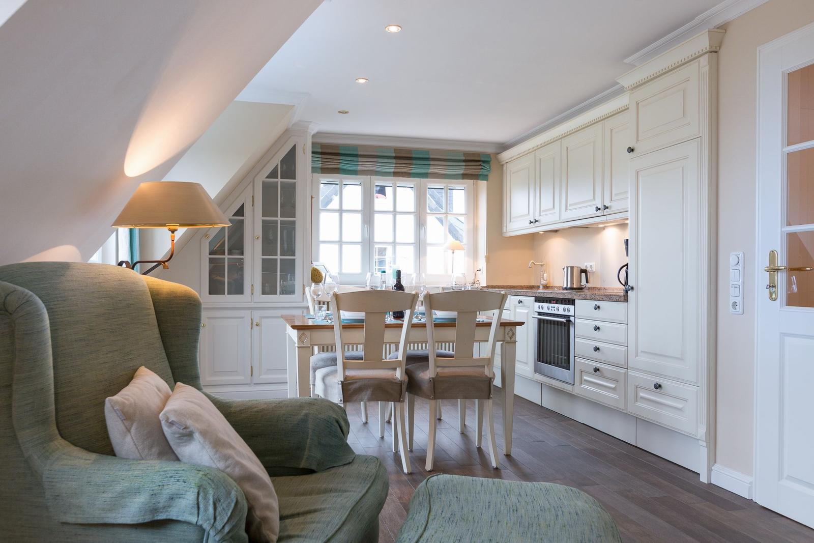 Dining area with kitchenette and seating under a sloped ceiling.