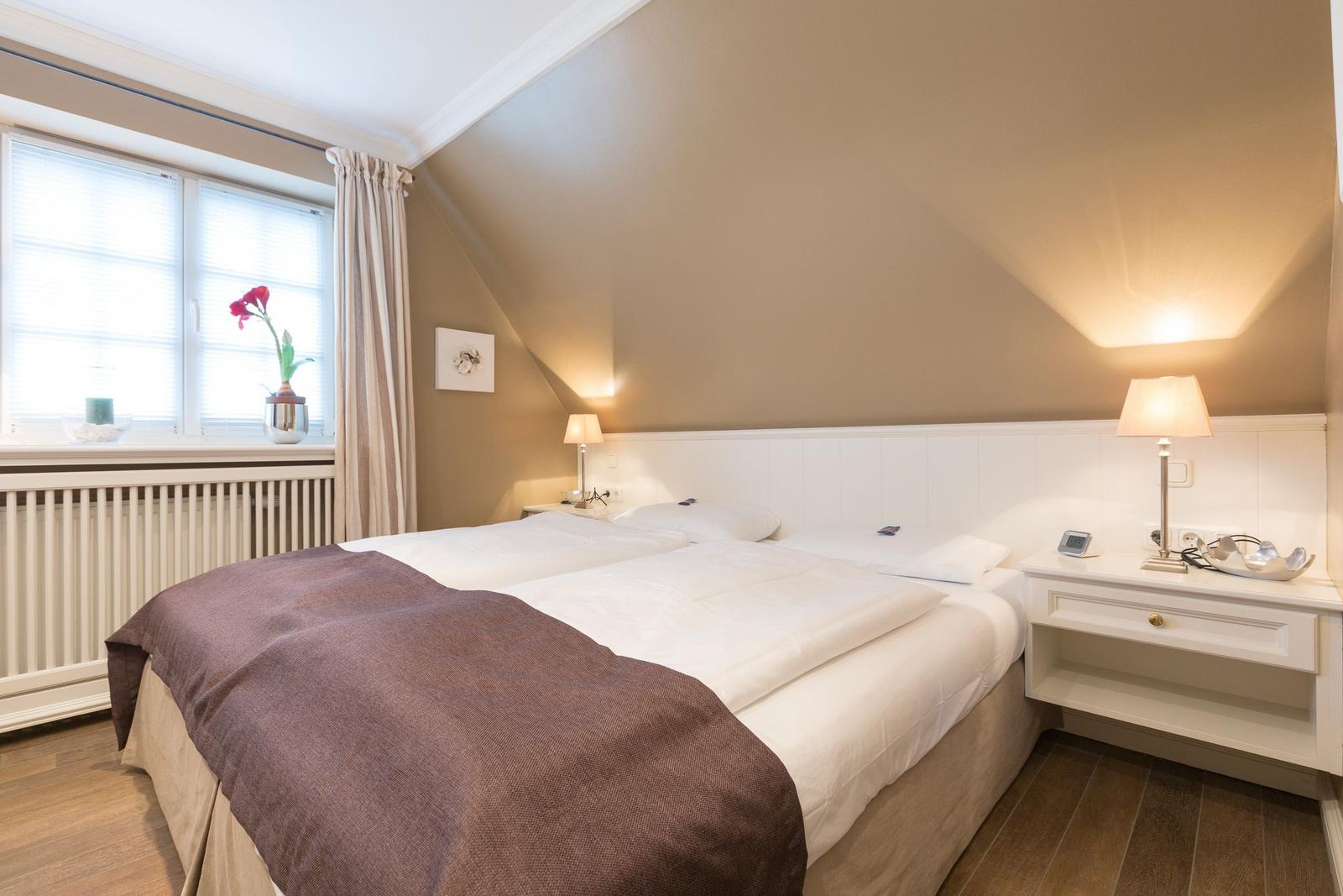 Bedroom with double bed, nightstand, and window with curtains.