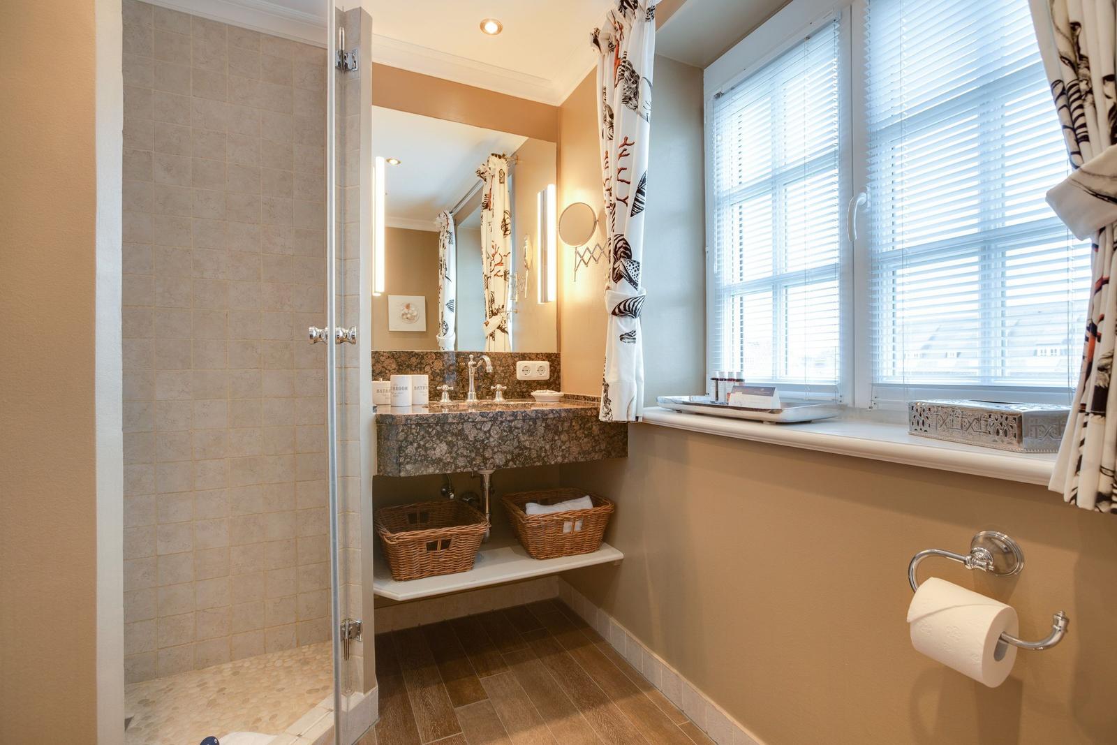 Bathroom with shower, sink, and window with blinds.