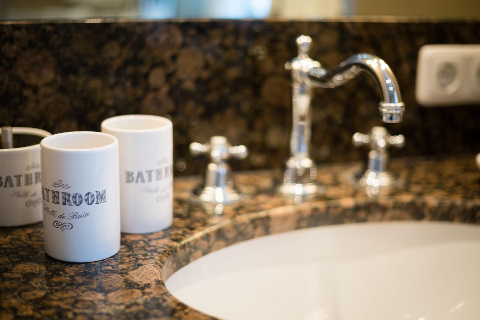 Bathroom with marble countertop and chrome faucets.