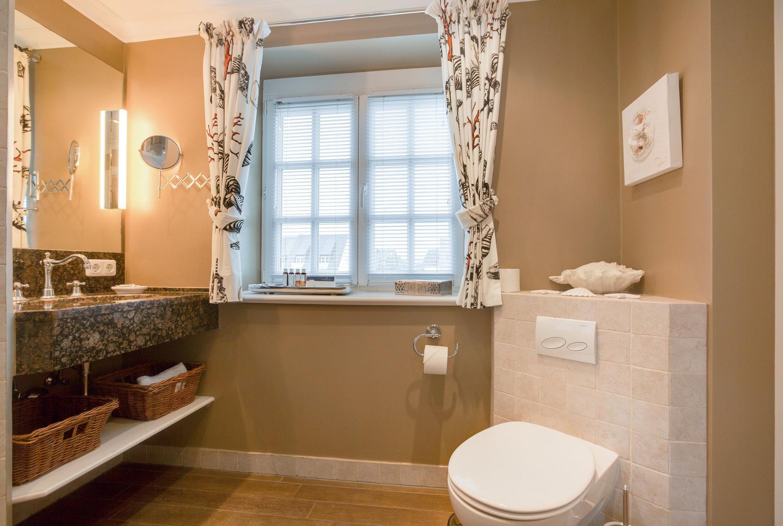 Bathroom with sink, toilet, and window with blinds.