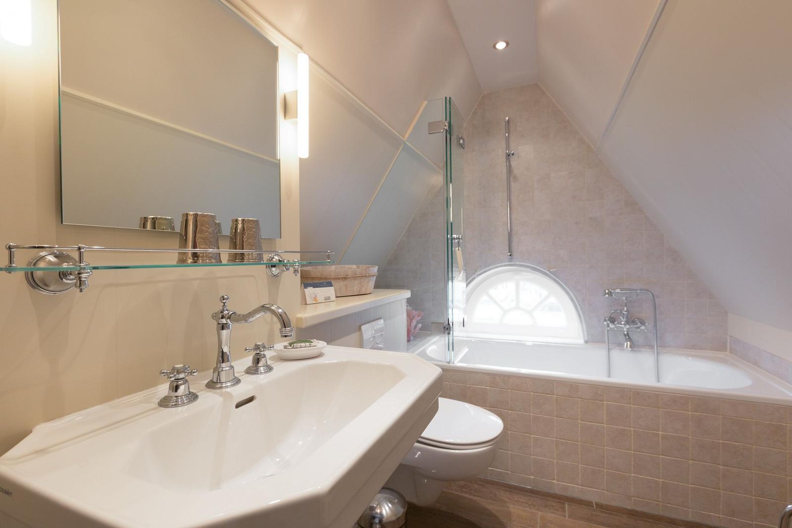 Bathroom with sink, mirror, bathtub, and shower under sloped ceilings.