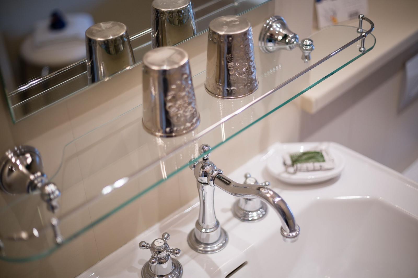 Bathroom with mirror, glass shelf, and chrome faucet