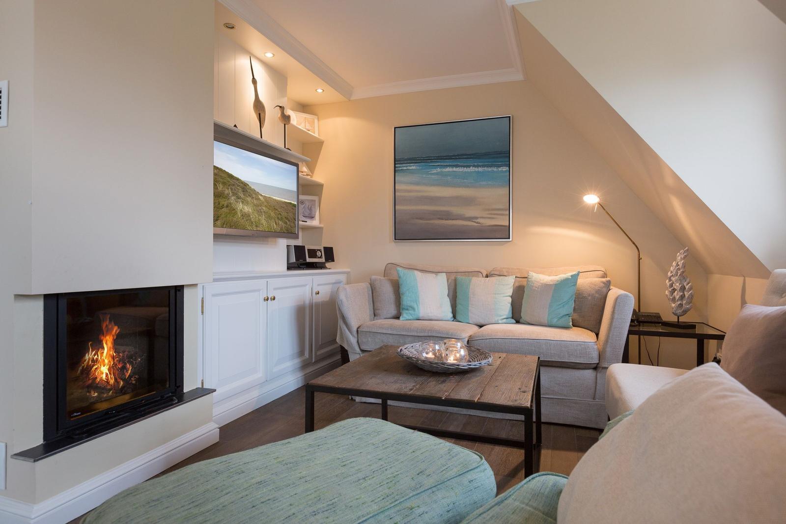 Living room with fireplace, sofa, and TV mounted on the wall.