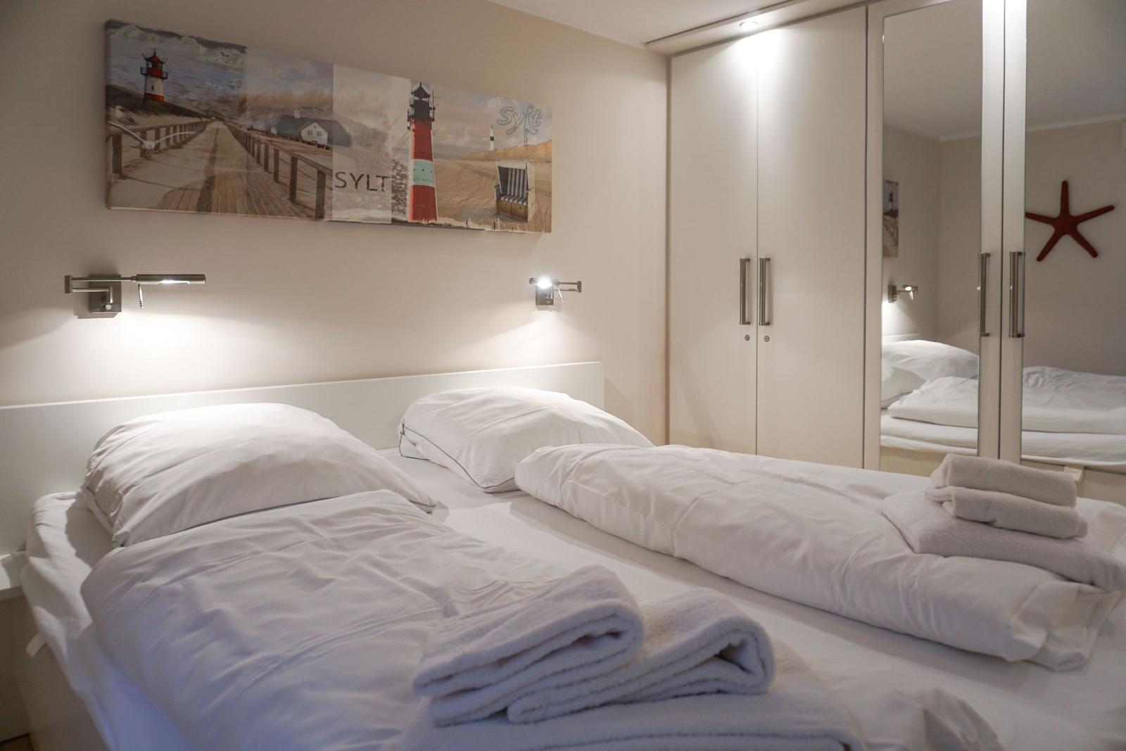 Zimmer mit Doppelbett, Wandbild und Spiegelschrank.