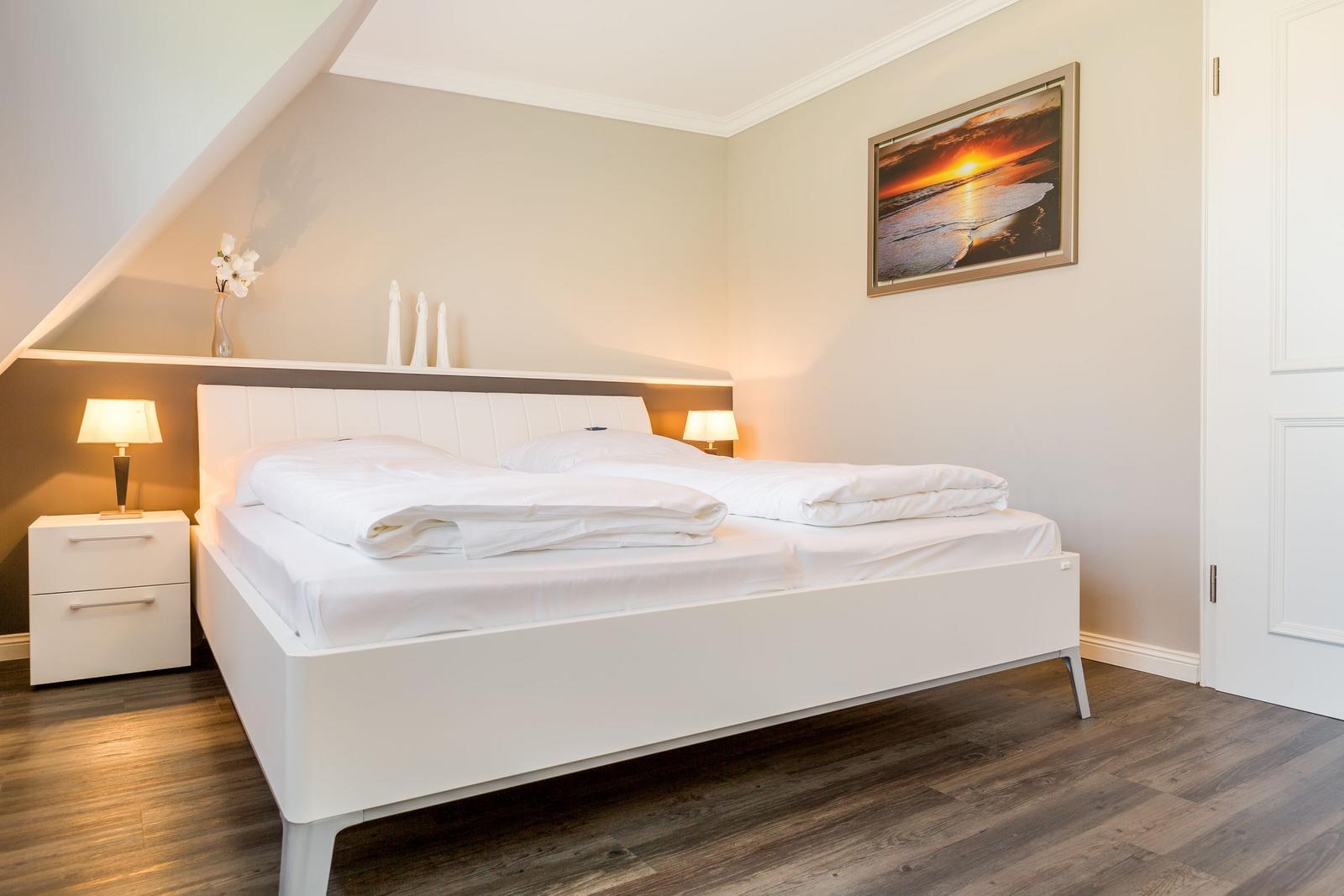 Bedroom with white bed, two nightstands, and wall picture.