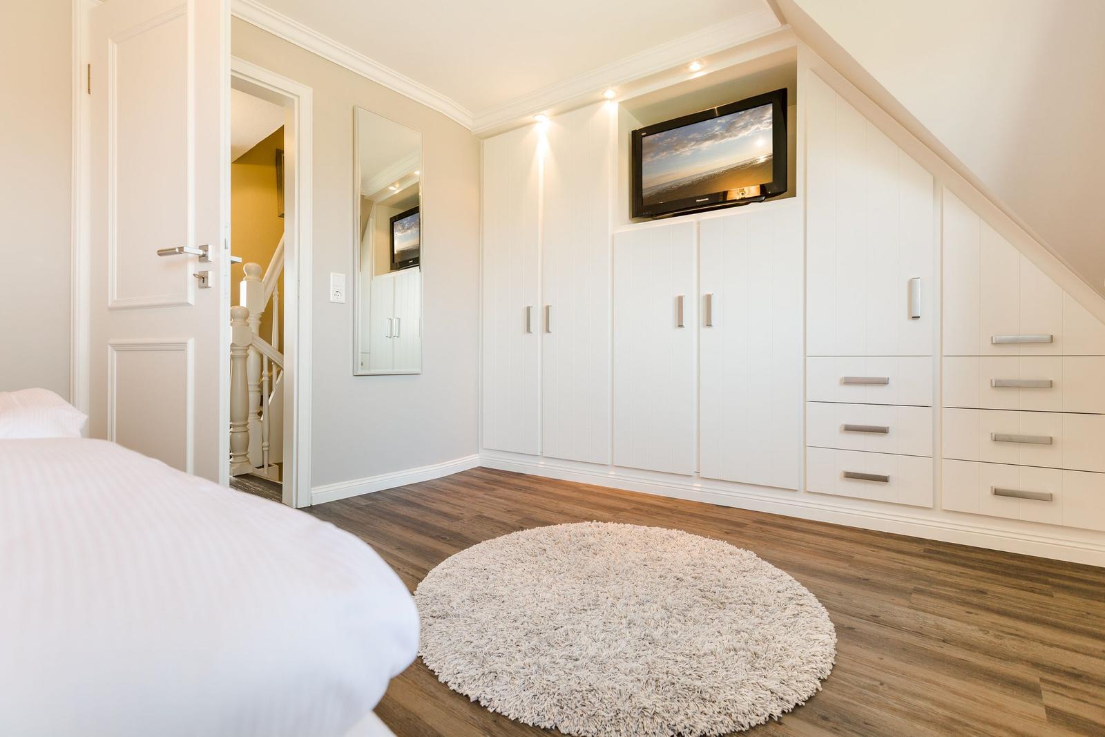 Bedroom with white closet, TV, and round rug.