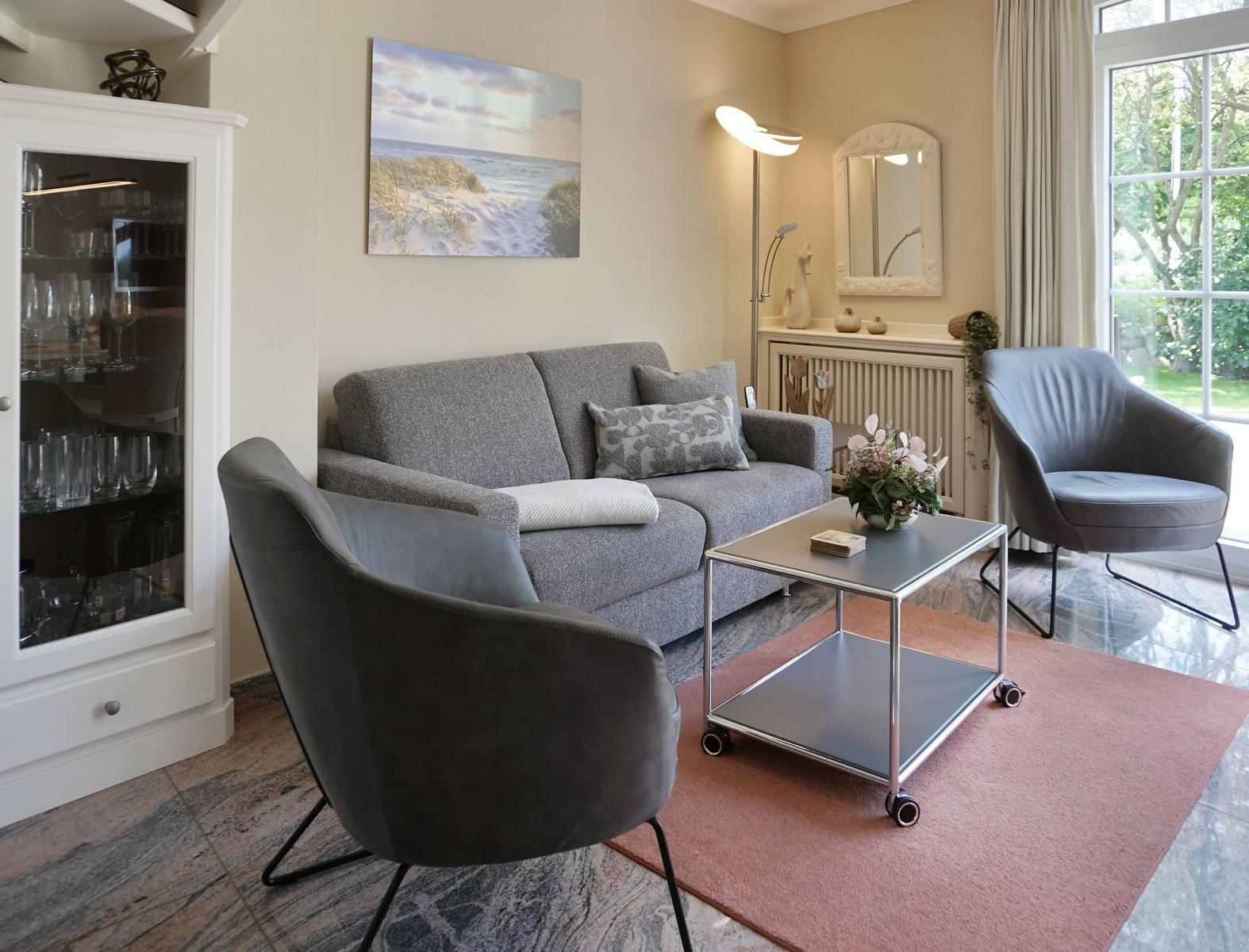 Living room with gray sofa, two armchairs, and a glass display cabinet.