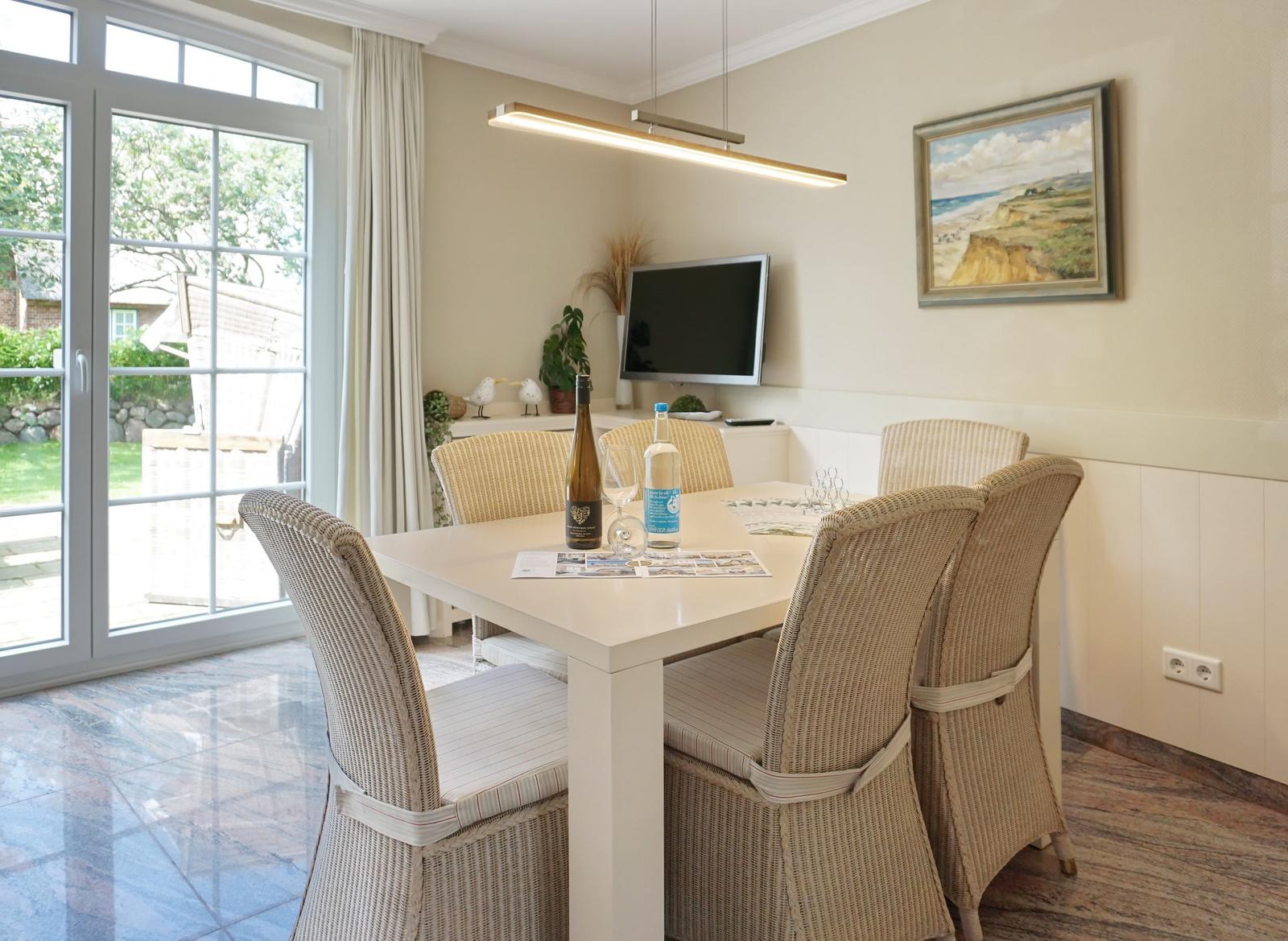 Dining room with table, chairs, and TV. Glass door leads to terrace.