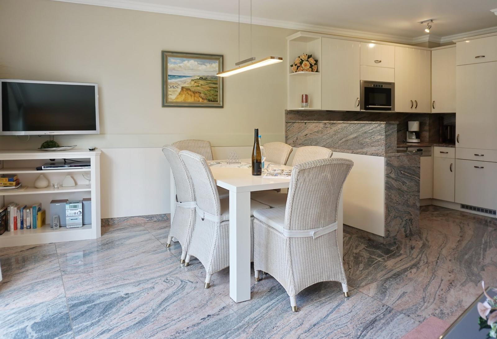 Dining area with table, chairs, and kitchen. Marble floor and wall picture.