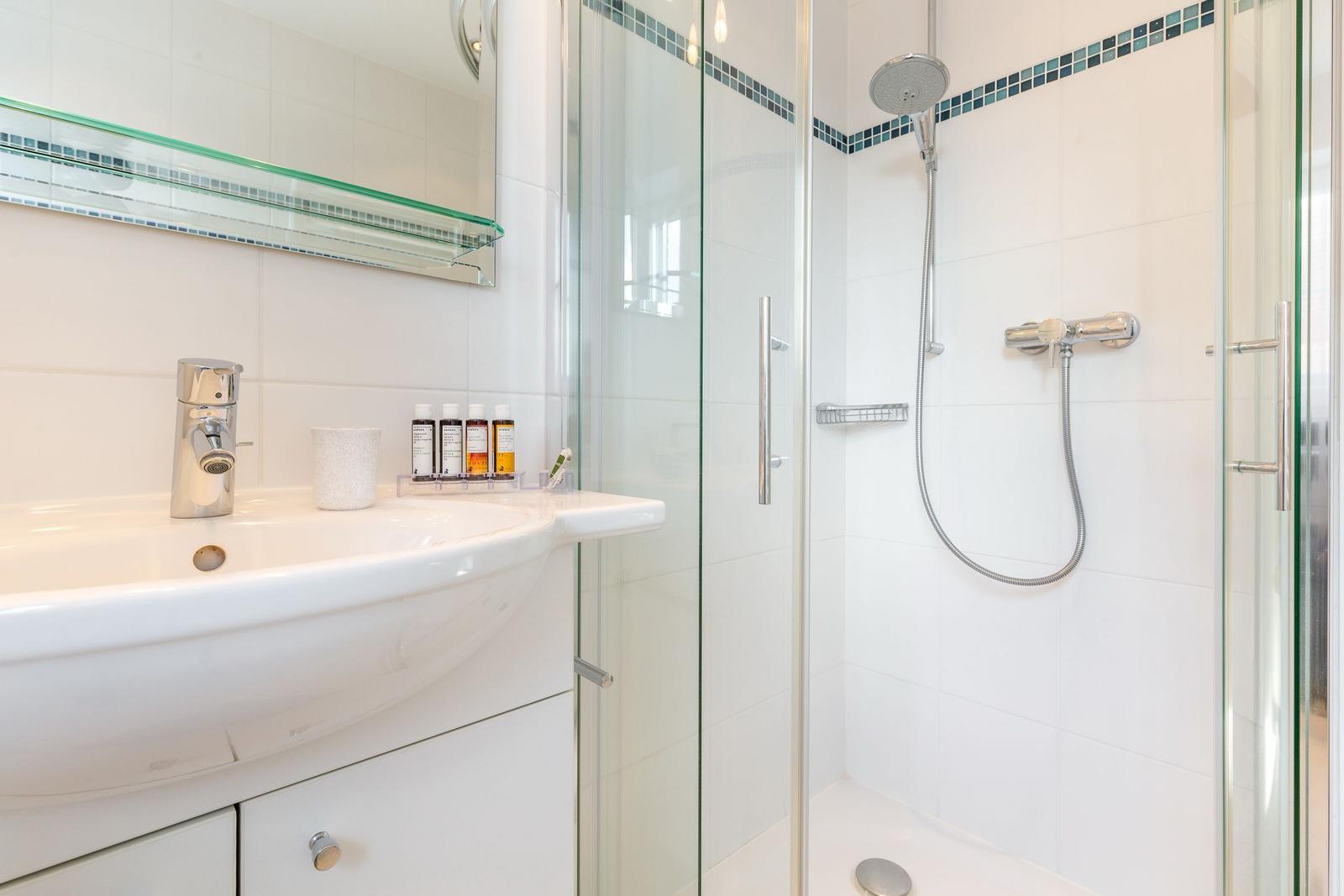 Badezimmer mit Dusche, Waschbecken und Spiegel