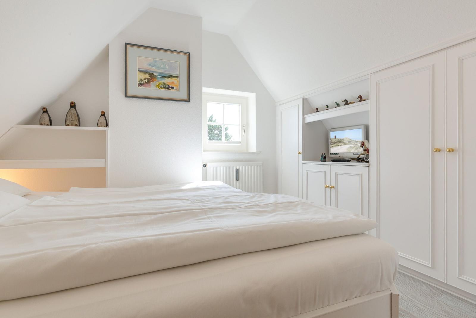 Schlafzimmer mit Bett, Schrank und Fenster. Wandbild und Vogelskulpturen.