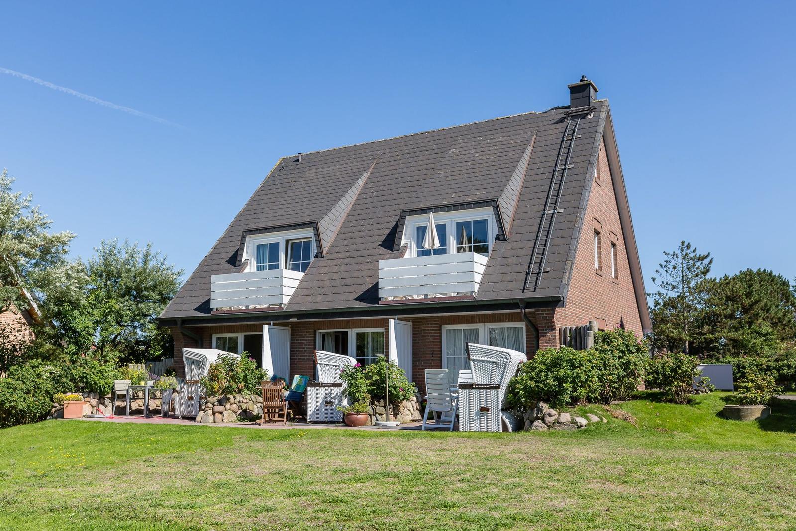 Haus mit Dachbodenfenstern und Terrasse im Garten.