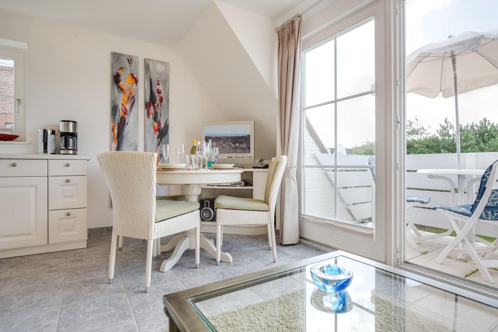 Esszimmer mit Tisch, Stühlen und Blick auf Balkon mit Sonnenschirm.