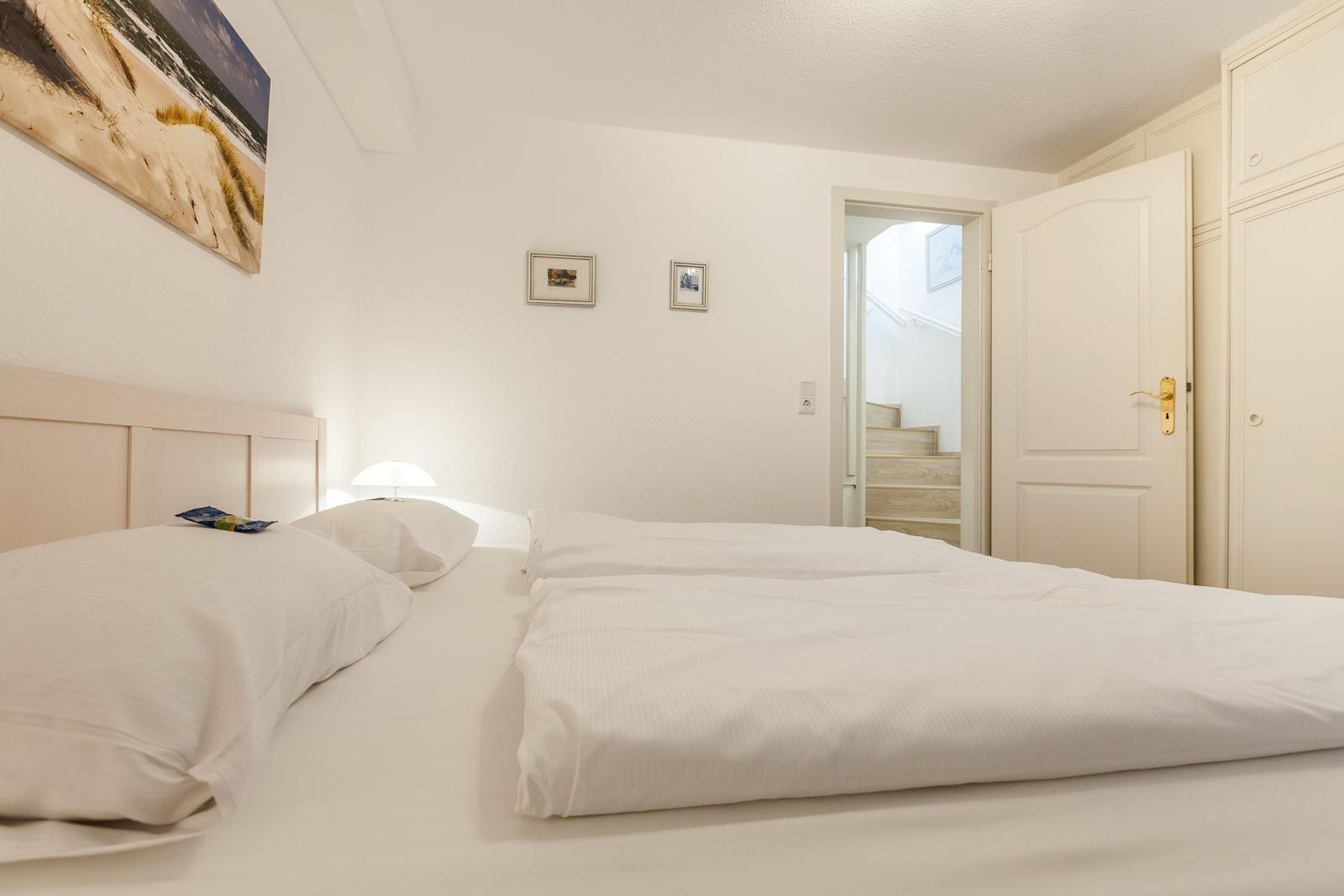 Bedroom with bed, wall art, and door to staircase