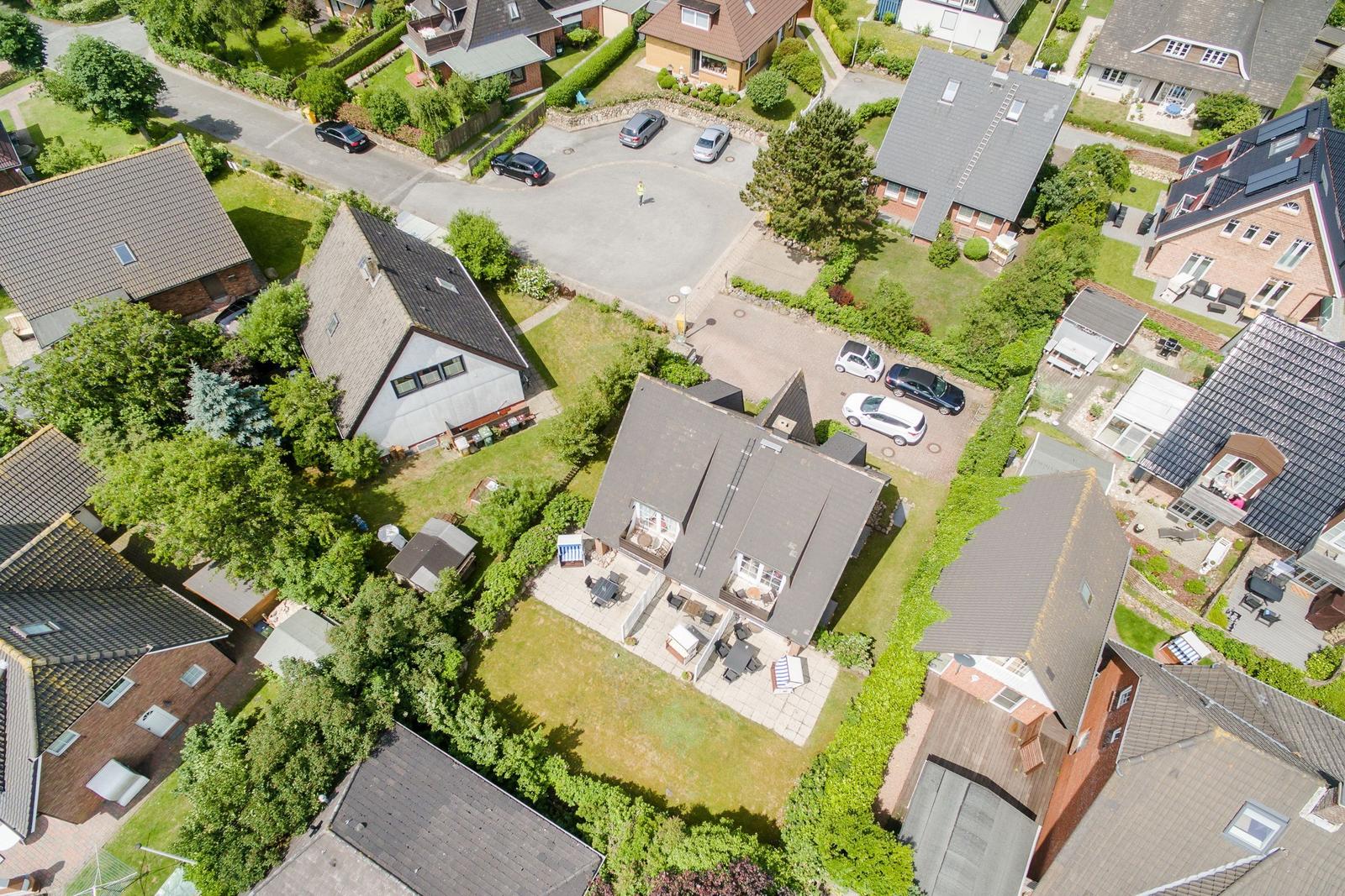 Aerial view of a residential area with multiple houses and well-kept gardens.