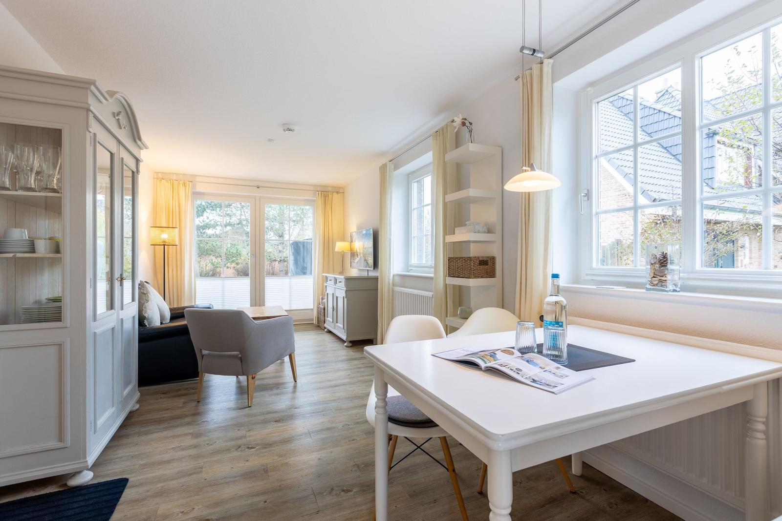 Wohn- und Essbereich mit Tisch, Stühlen und Fenstern.