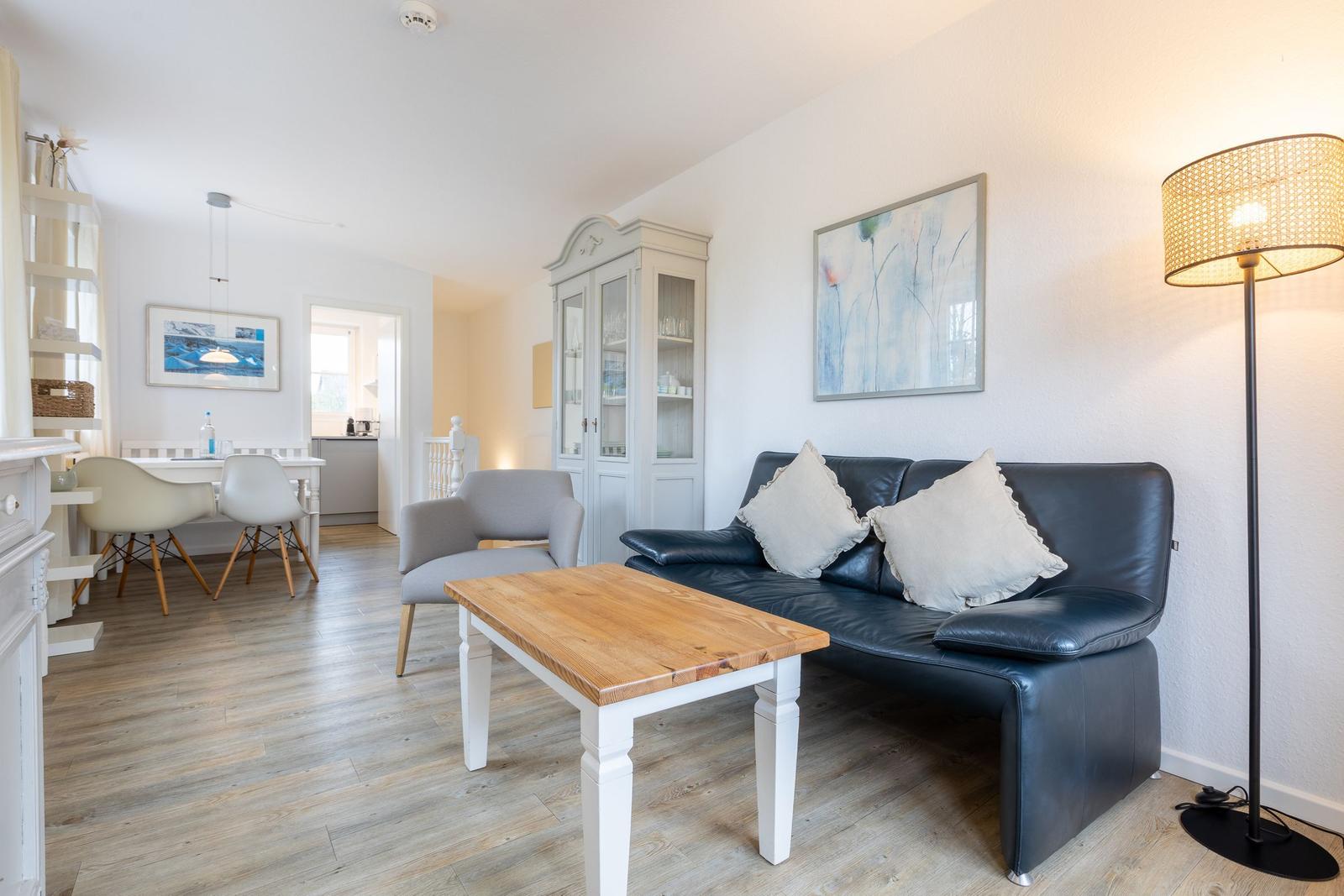 Wohn- und Essbereich mit Sofa, Tisch und Küchenbereich im Hintergrund.