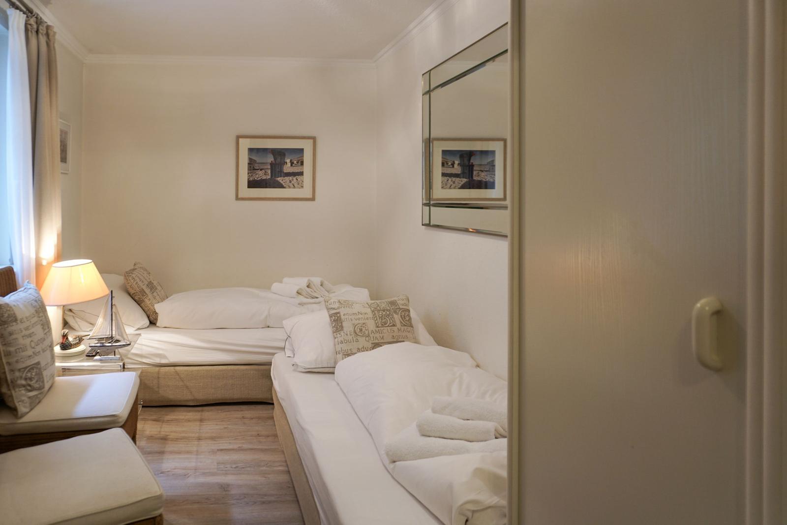 Zwei Betten mit weißen Bettwäsche, Wandbild und Spiegel an der Wand.