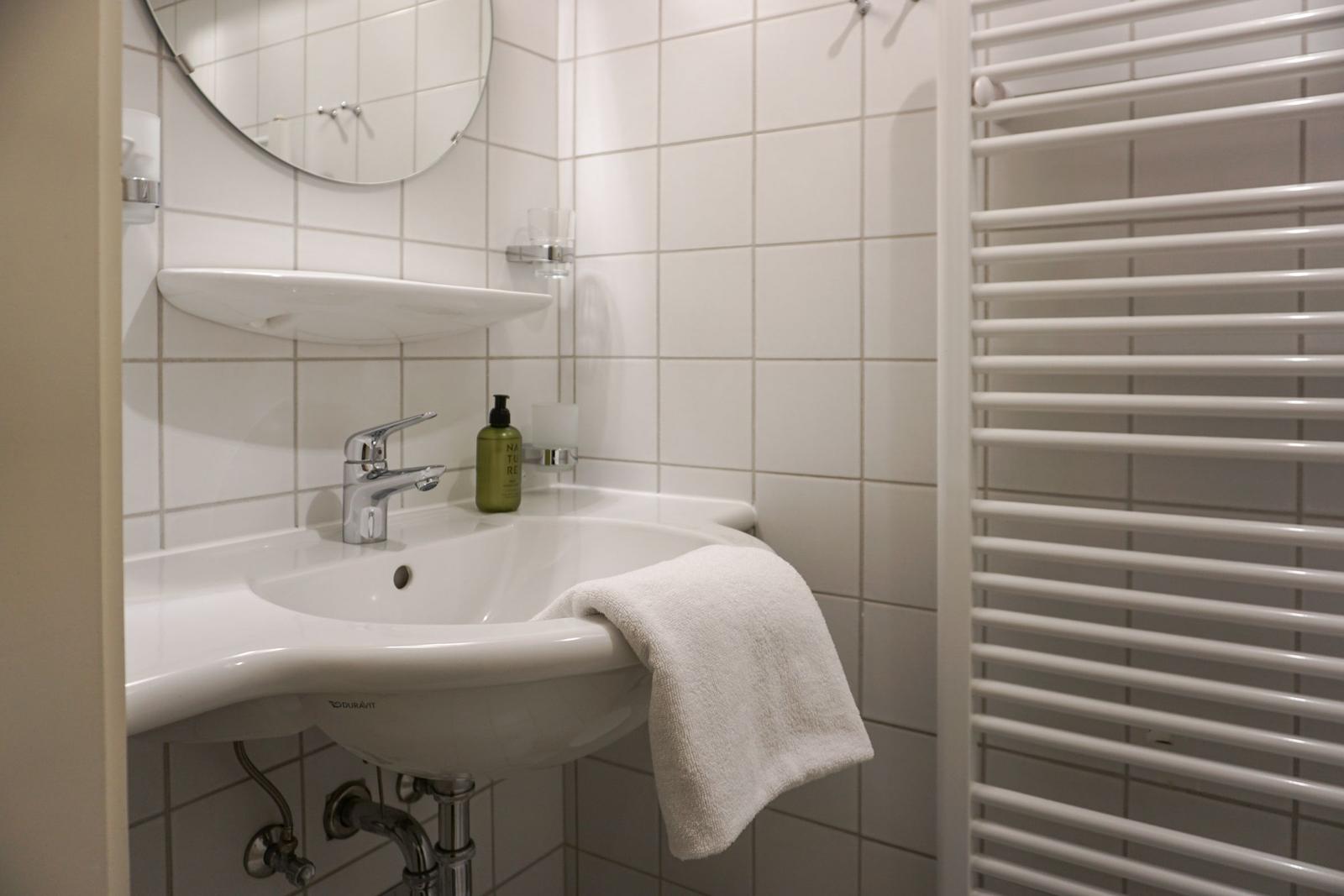 Badezimmer mit Waschbecken, Spiegel und Heizkörper
