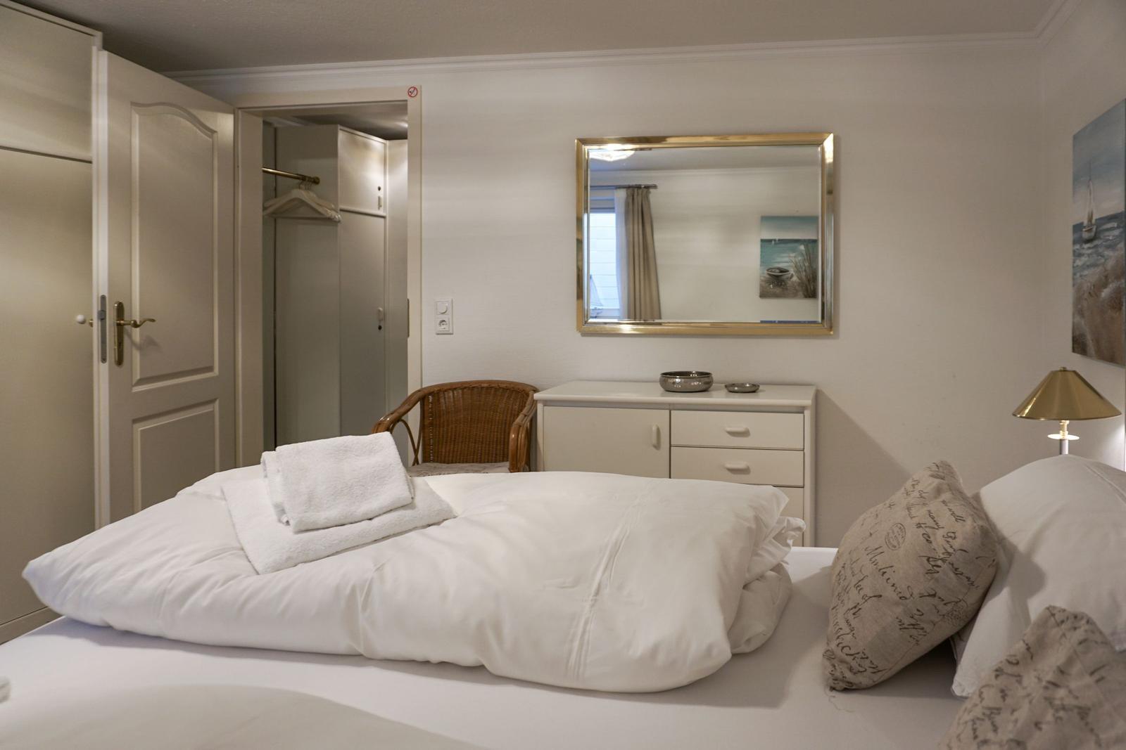 Schlafzimmer mit Bett, Kleiderschrank und Spiegel an der Wand.