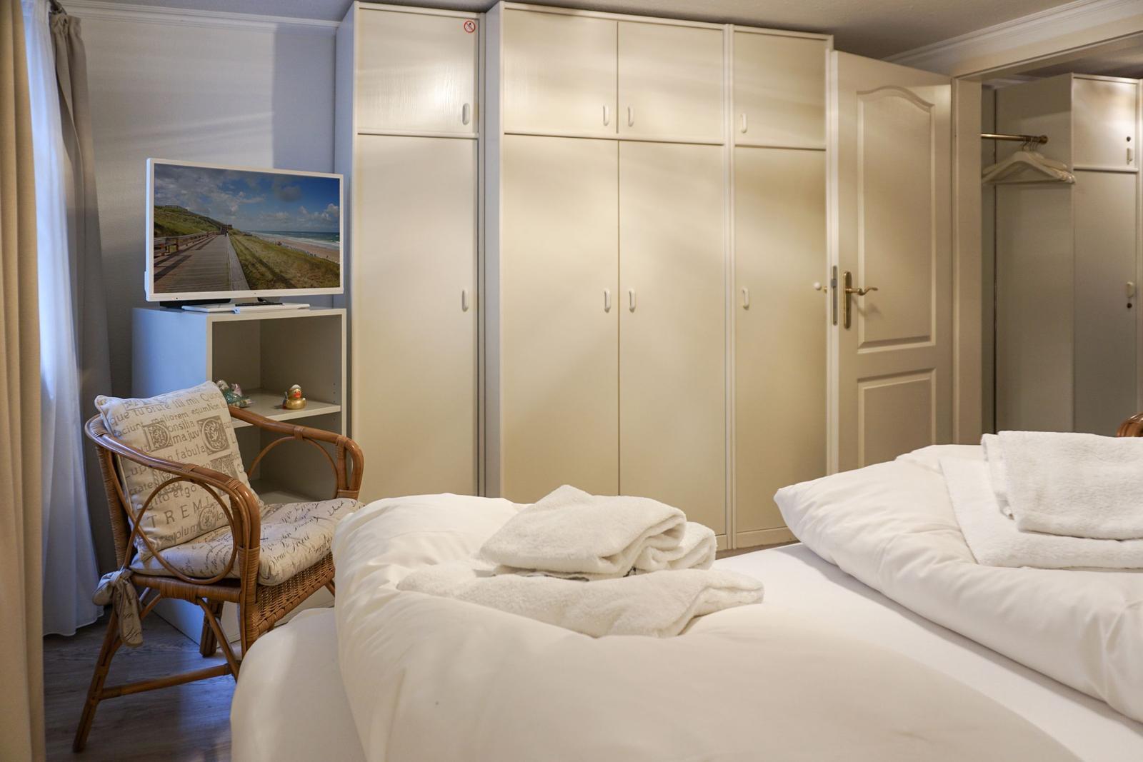 Schlafzimmer mit Bett, Kleiderschrank und Fernseher