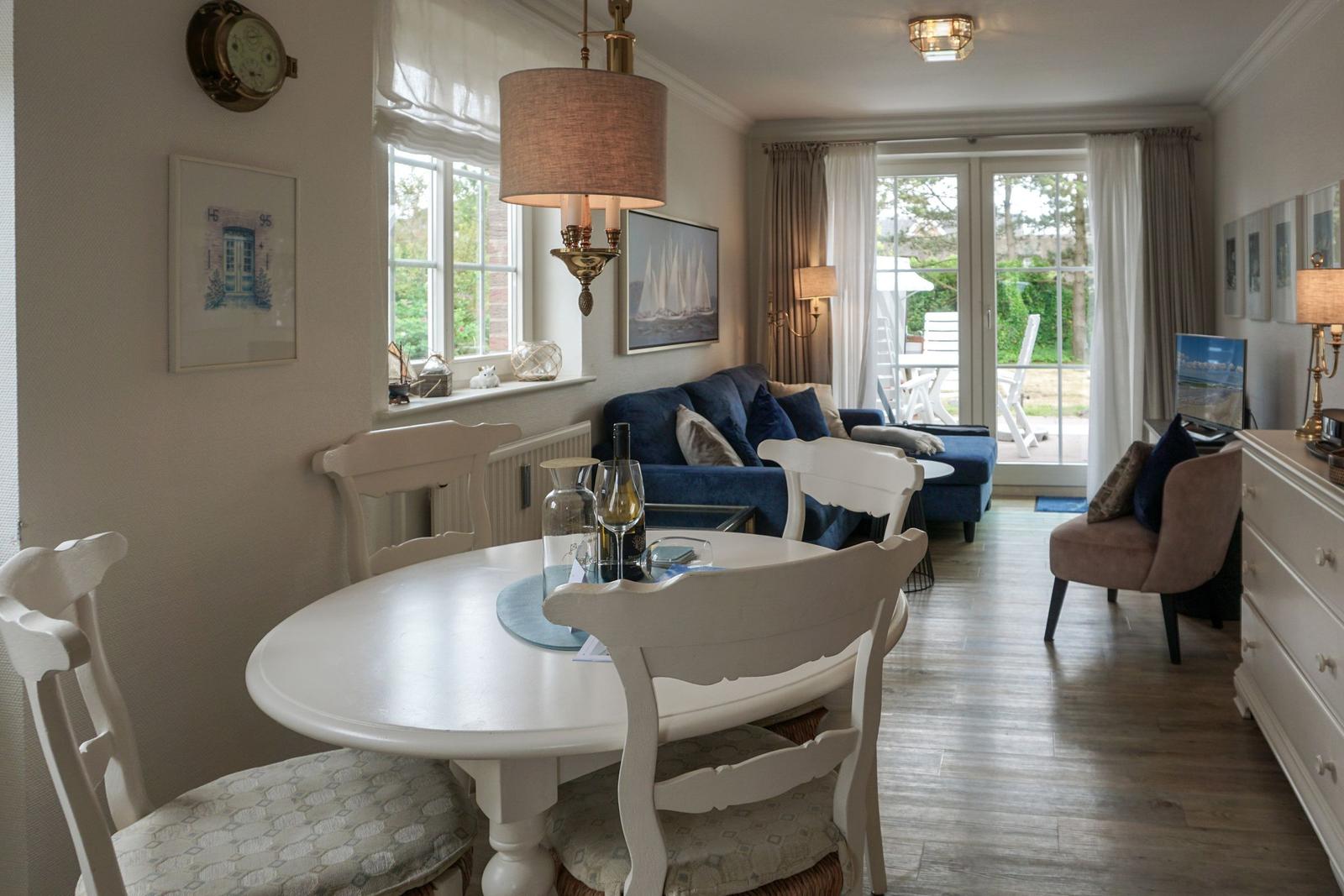 Esszimmer mit weißem Tisch und Stühlen. Wohnbereich mit Sofa und TV.