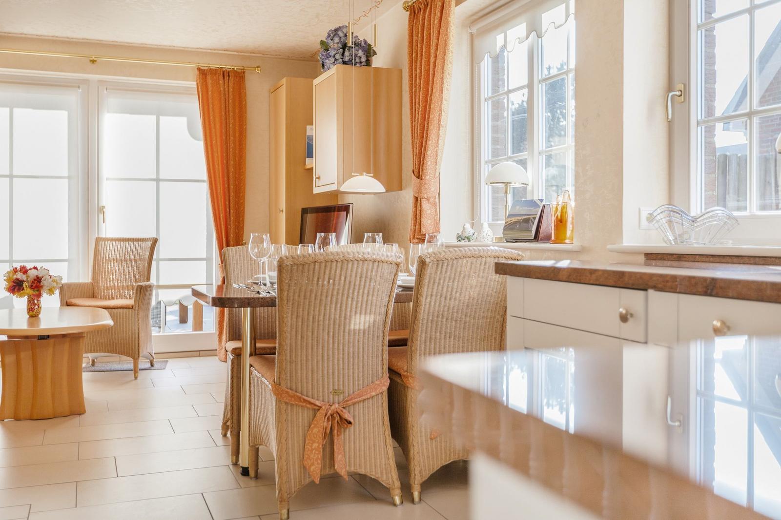 Essbereich mit Esstisch, Stühlen und Fenstern. Küche mit Arbeitsplatte und Schränken.