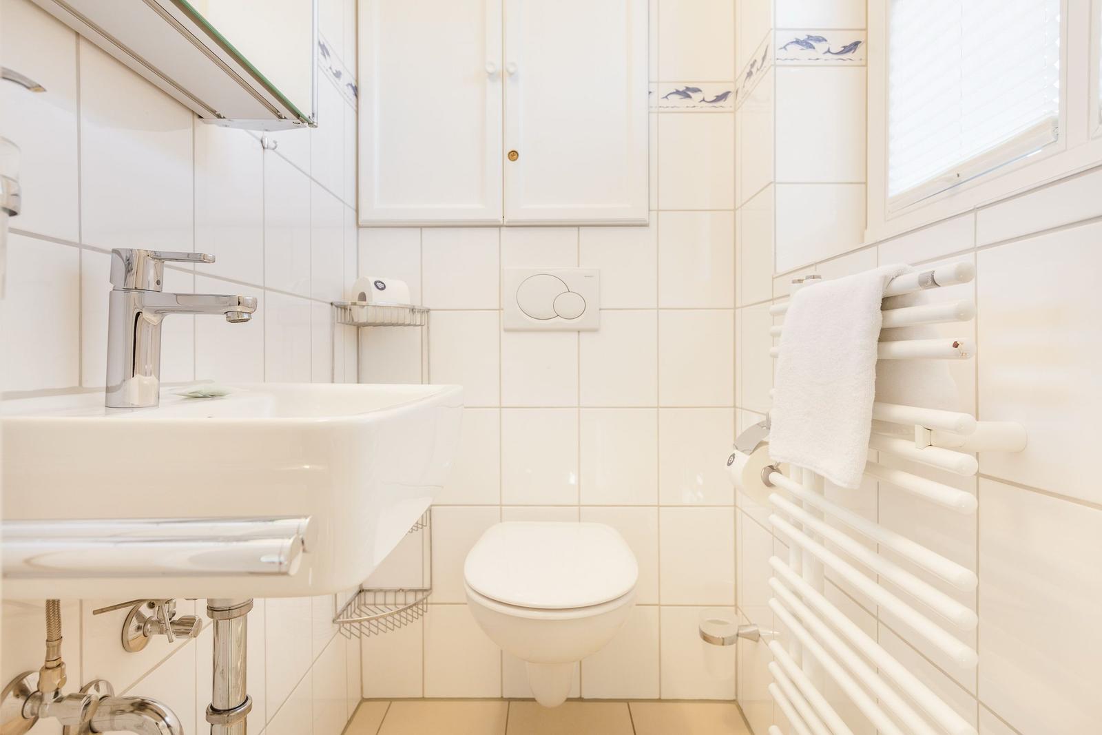 Badezimmer mit Waschbecken, Toilette und Handtuchhalter.