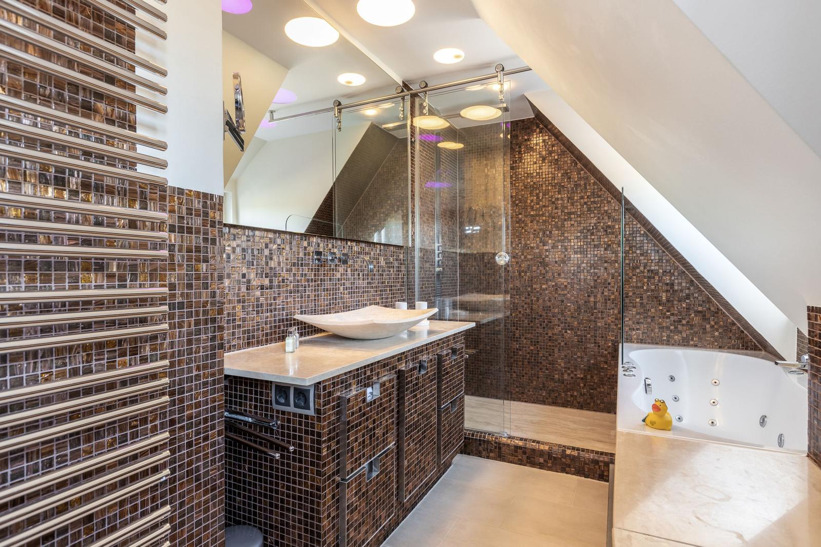 Dusche mit Glaswand, Badewanne und Waschbecken mit Mosaikwand
