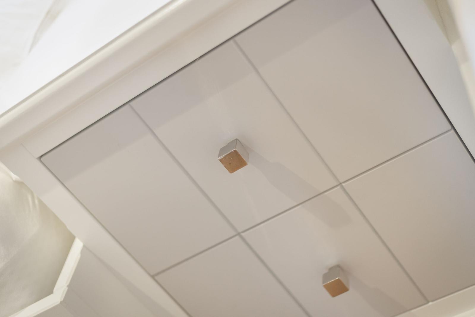 Weißer Schrank mit quadratischen Griffen und glatten Türen