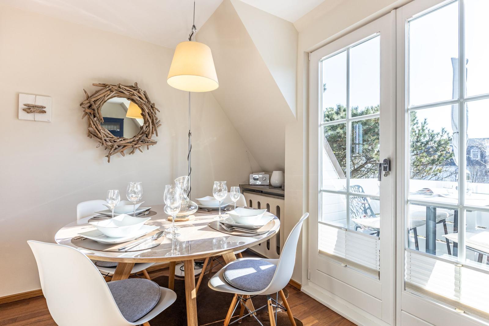 Runder Esstisch mit Stühlen und Fenster zur Terrasse.