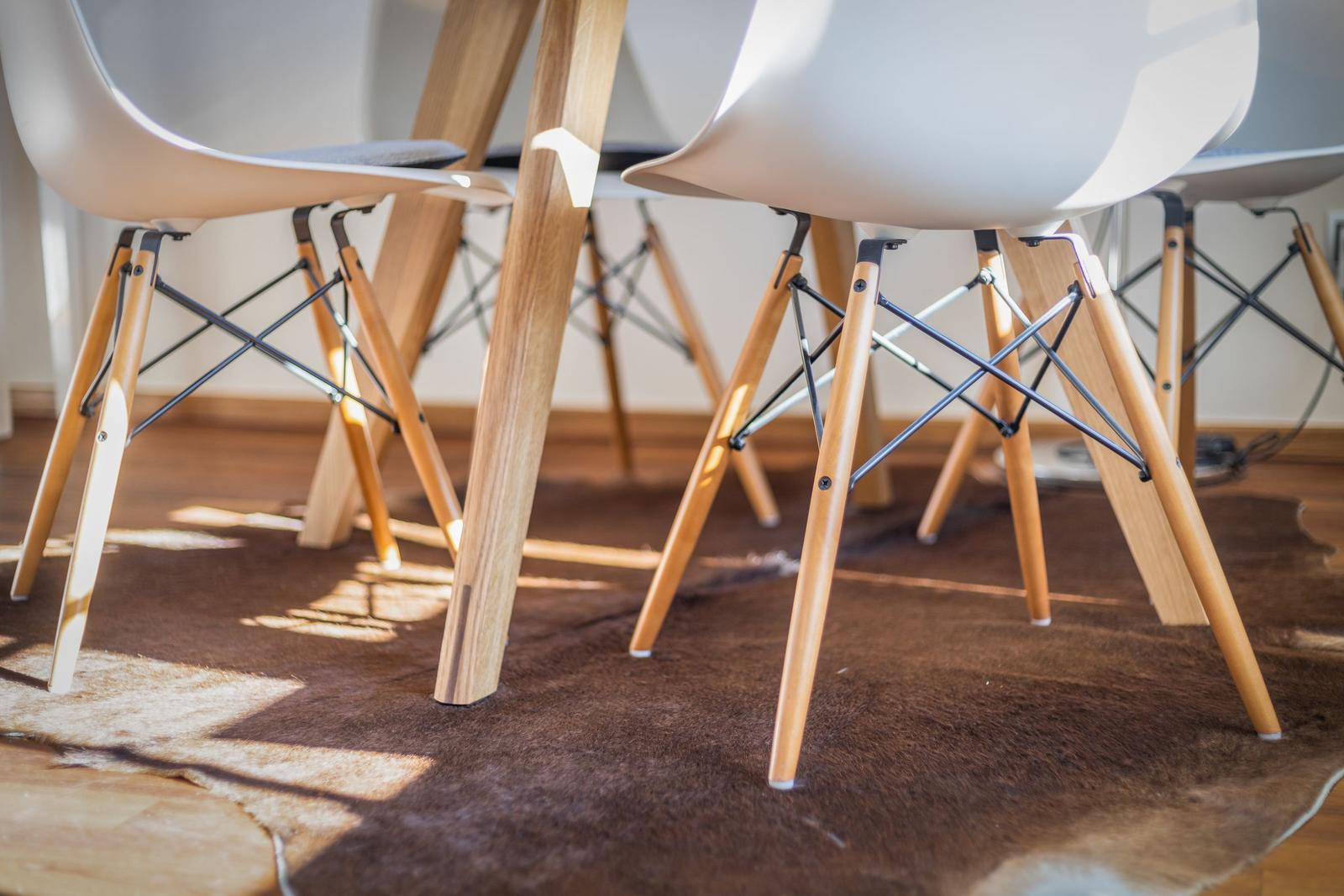 Moderne Stühle mit Holzbeinen stehen auf einem Fellteppich.