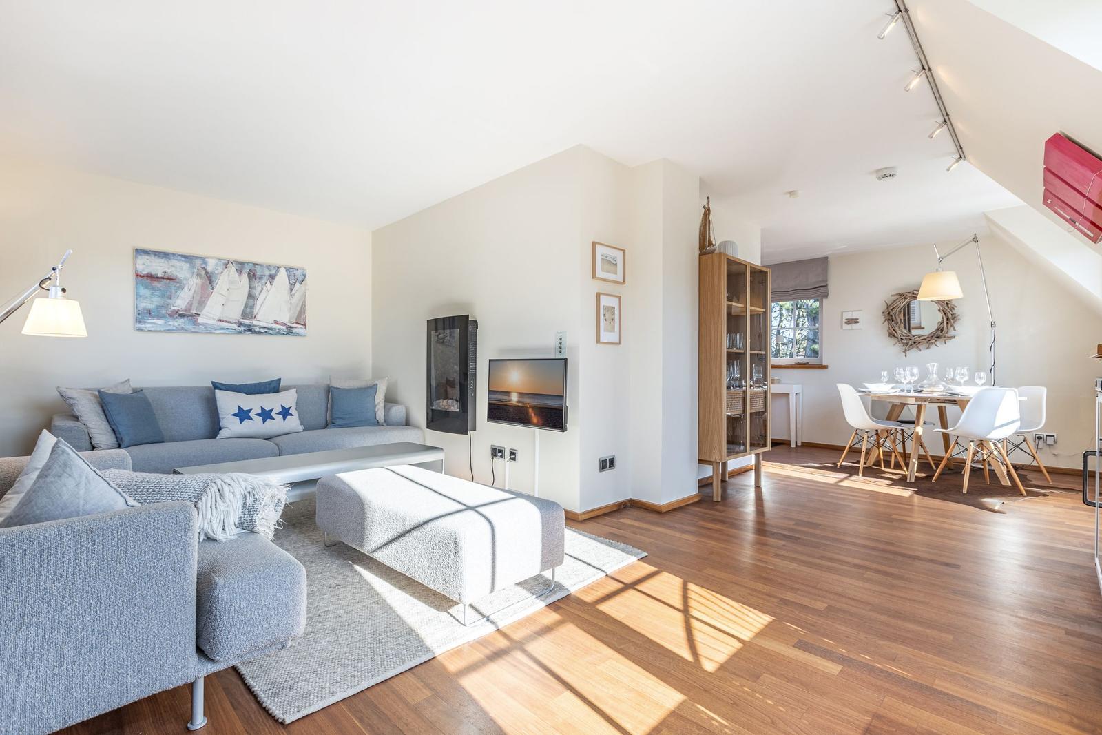 Wohn- und Essbereich mit Sofa, Fernseher und Holzboden.