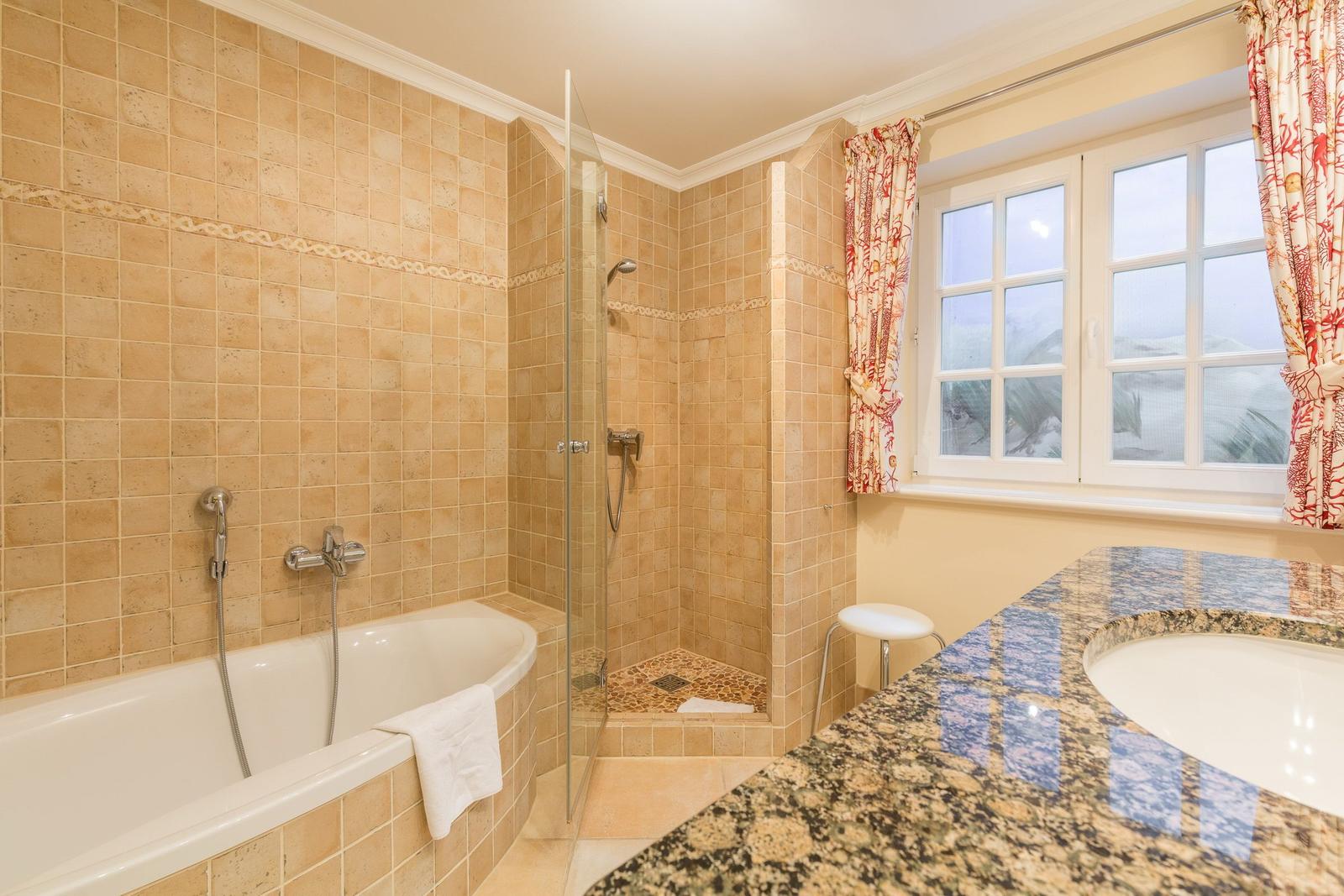 Bathroom with bathtub, shower, and sink with marble countertop.