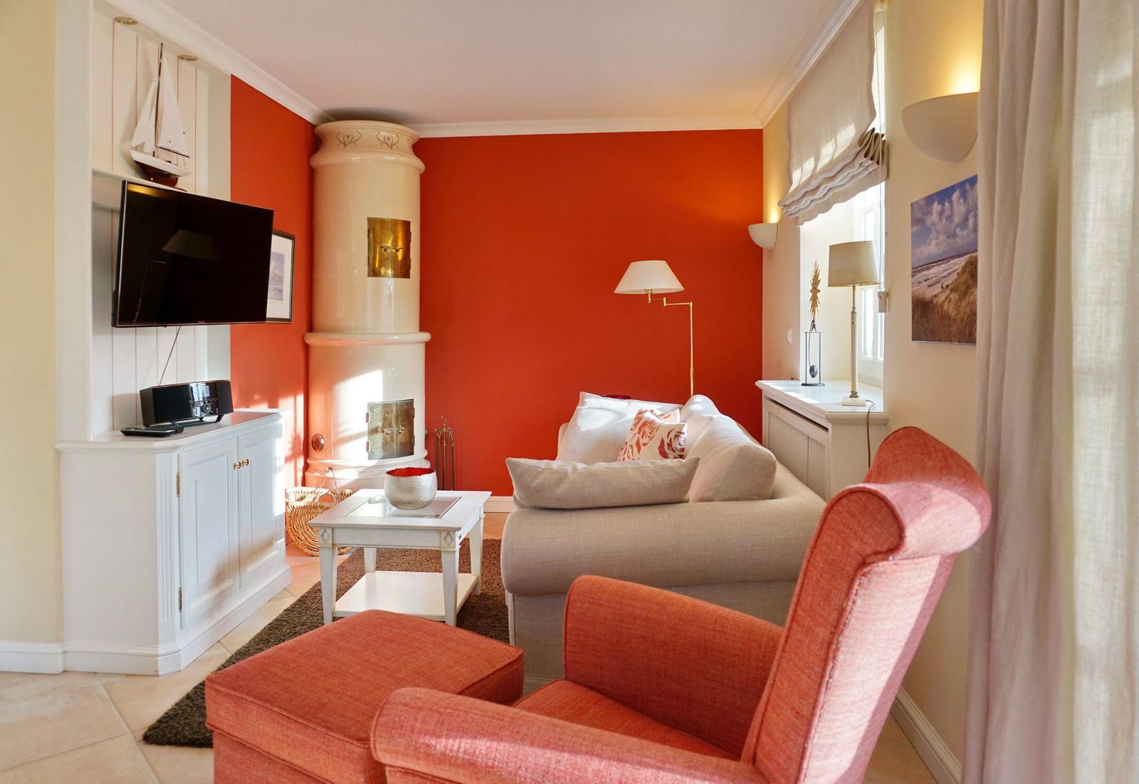 Living room with red wall, sofa, armchair, and fireplace.
