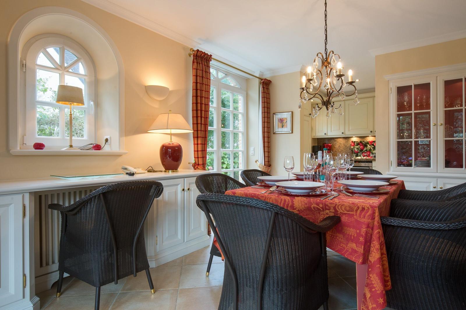 Dining room with set table, wicker chairs, and windows with curtains.