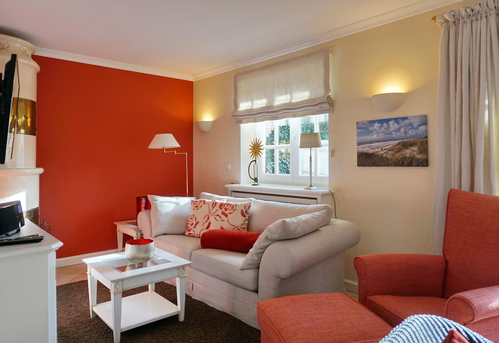 Living room with sofa, armchair, and window. Wall in red, furniture in white and red.