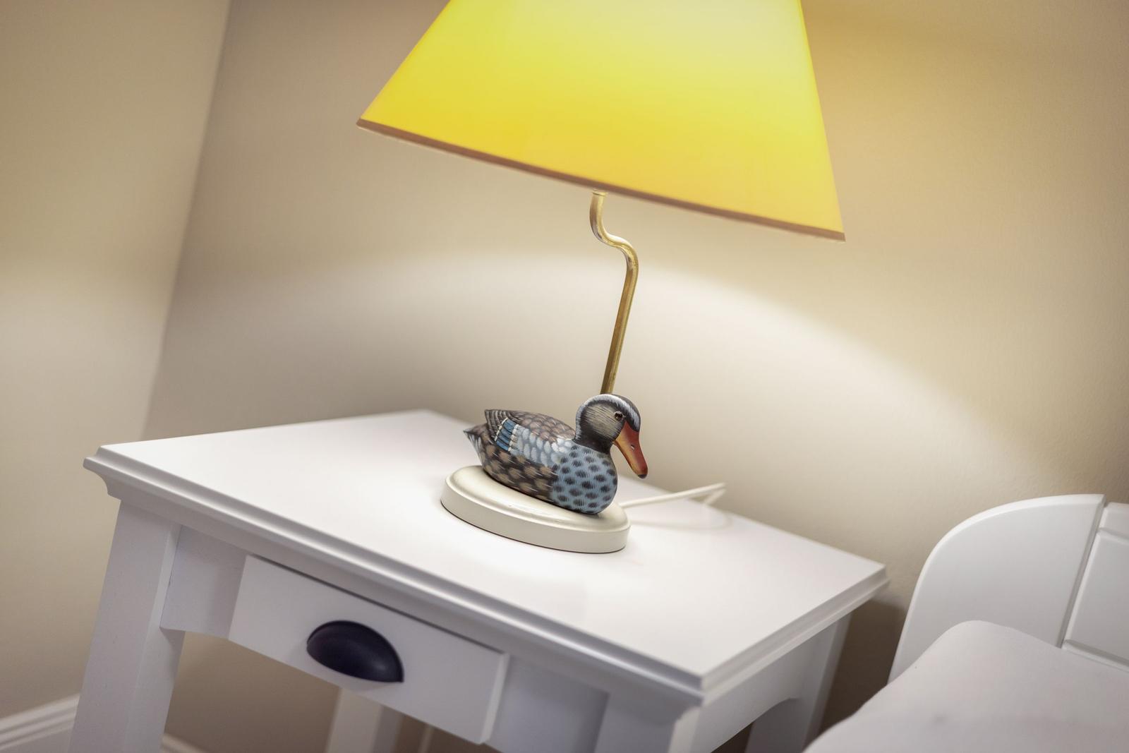 Tischlampe mit Entenfigur auf weißem Nachttisch