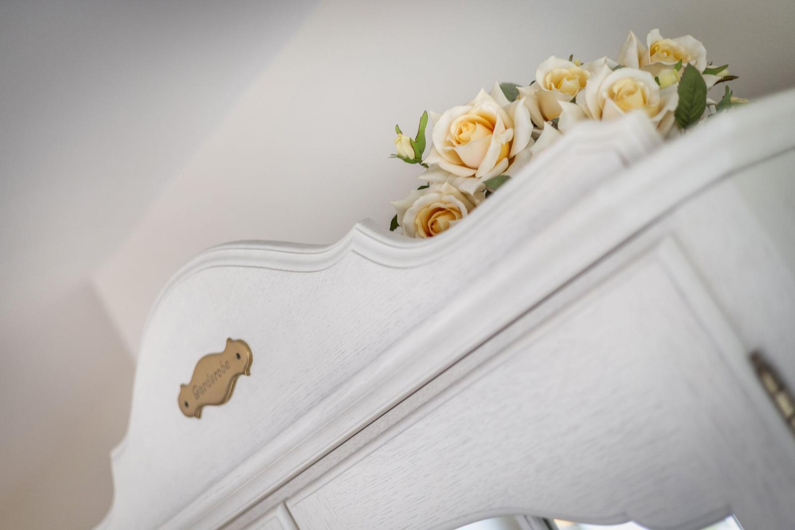 Weißer Schrank mit Blumen und goldenem Schild