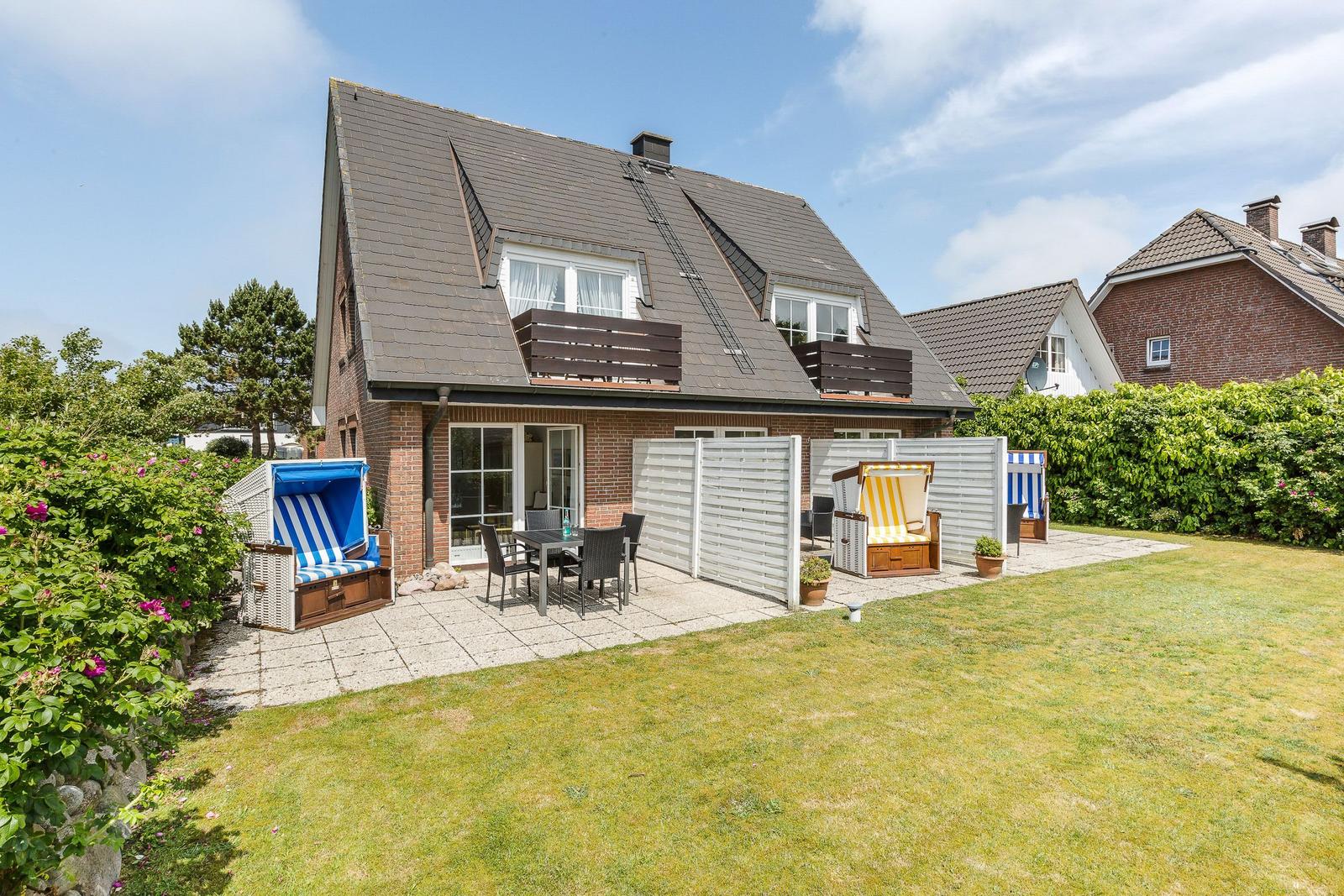 Haus mit Terrasse, Garten und Strandkörben.