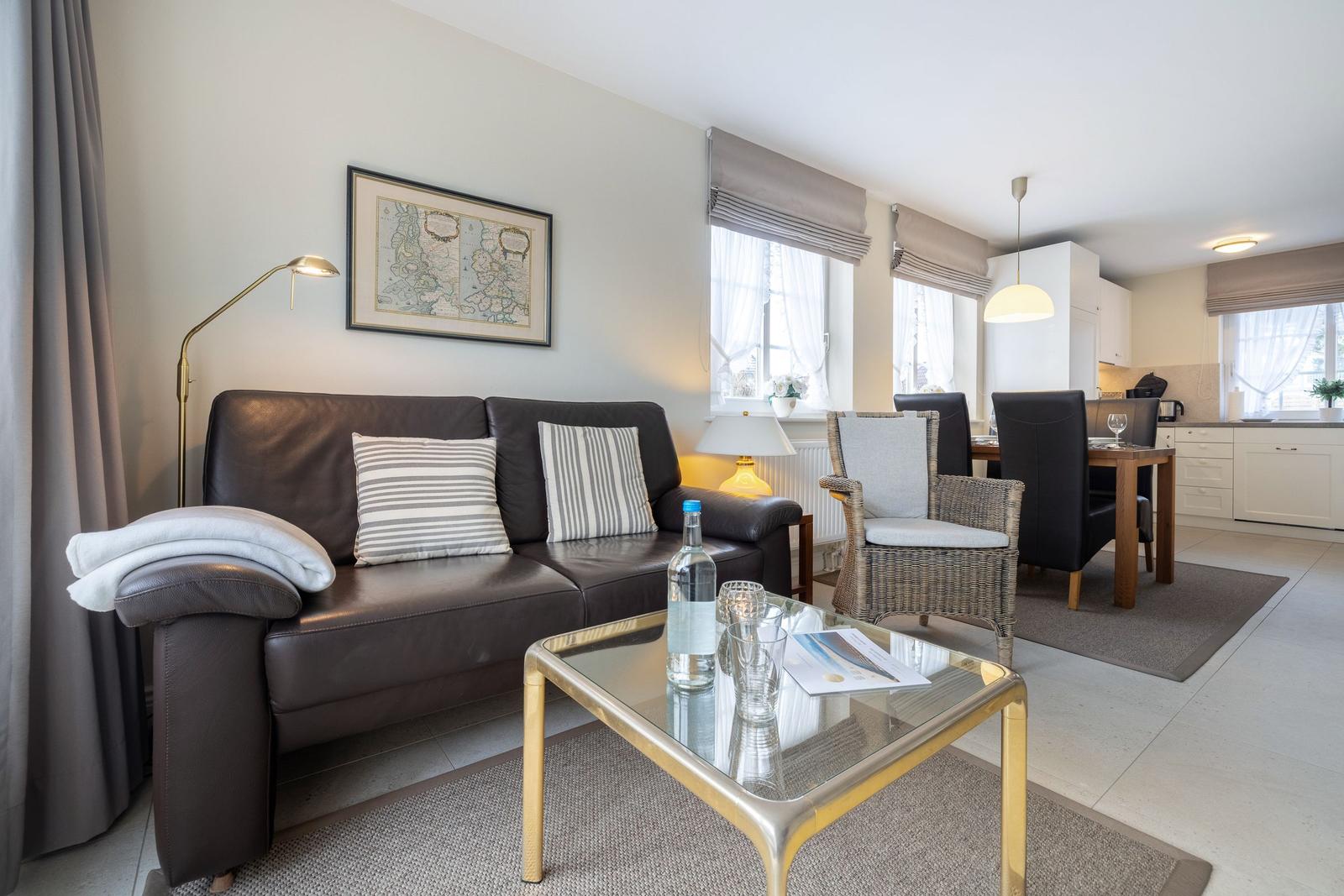Wohnzimmer mit Ledersofa, Glas-Tisch und Essbereich im Hintergrund.