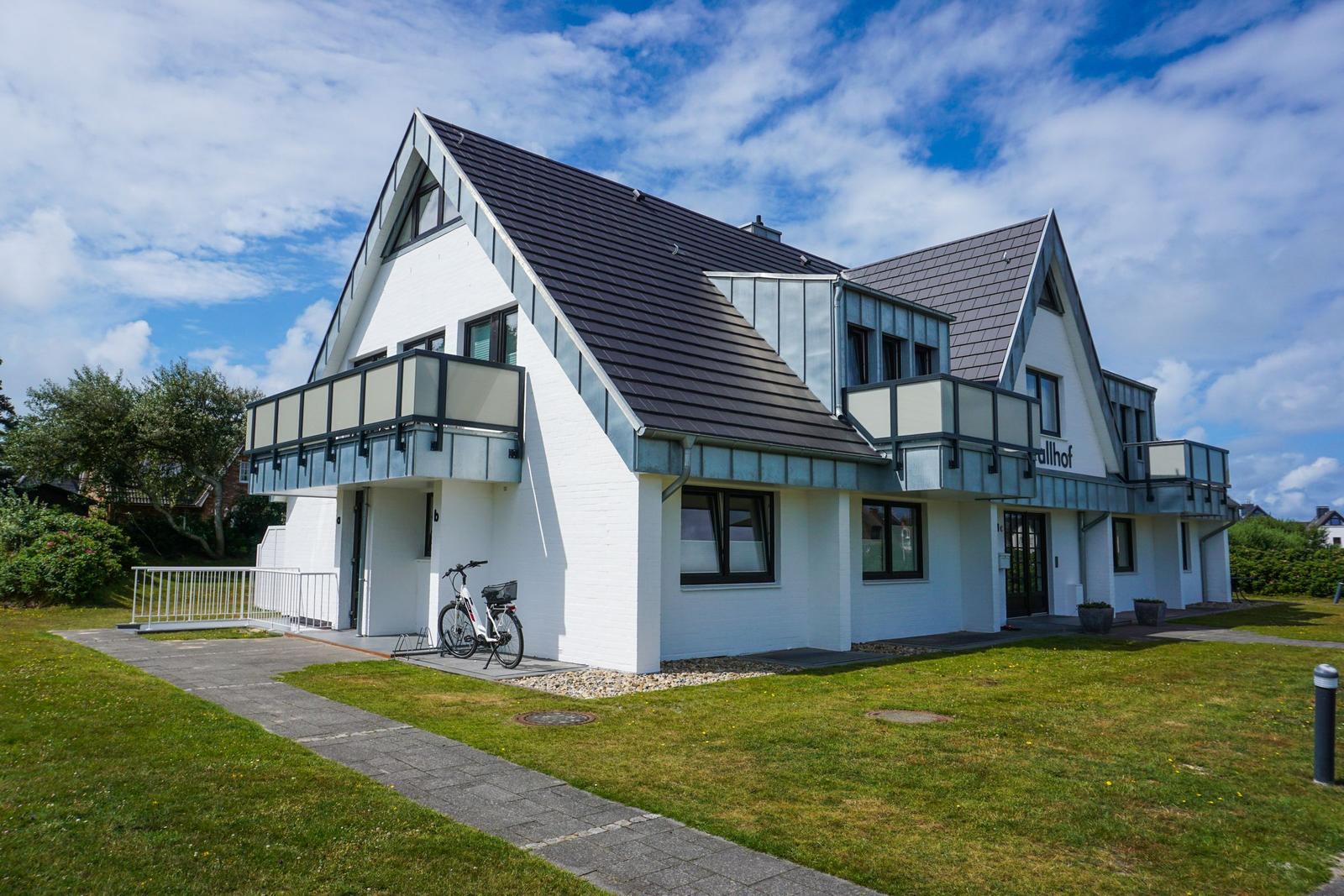 Modern house with balconies and bicycle. Green lawn and clear view.