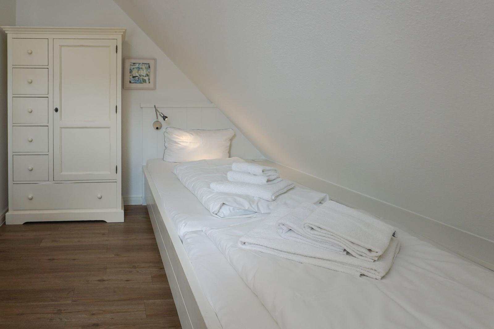 Bedroom with double bed, white wardrobe, and wooden floor.