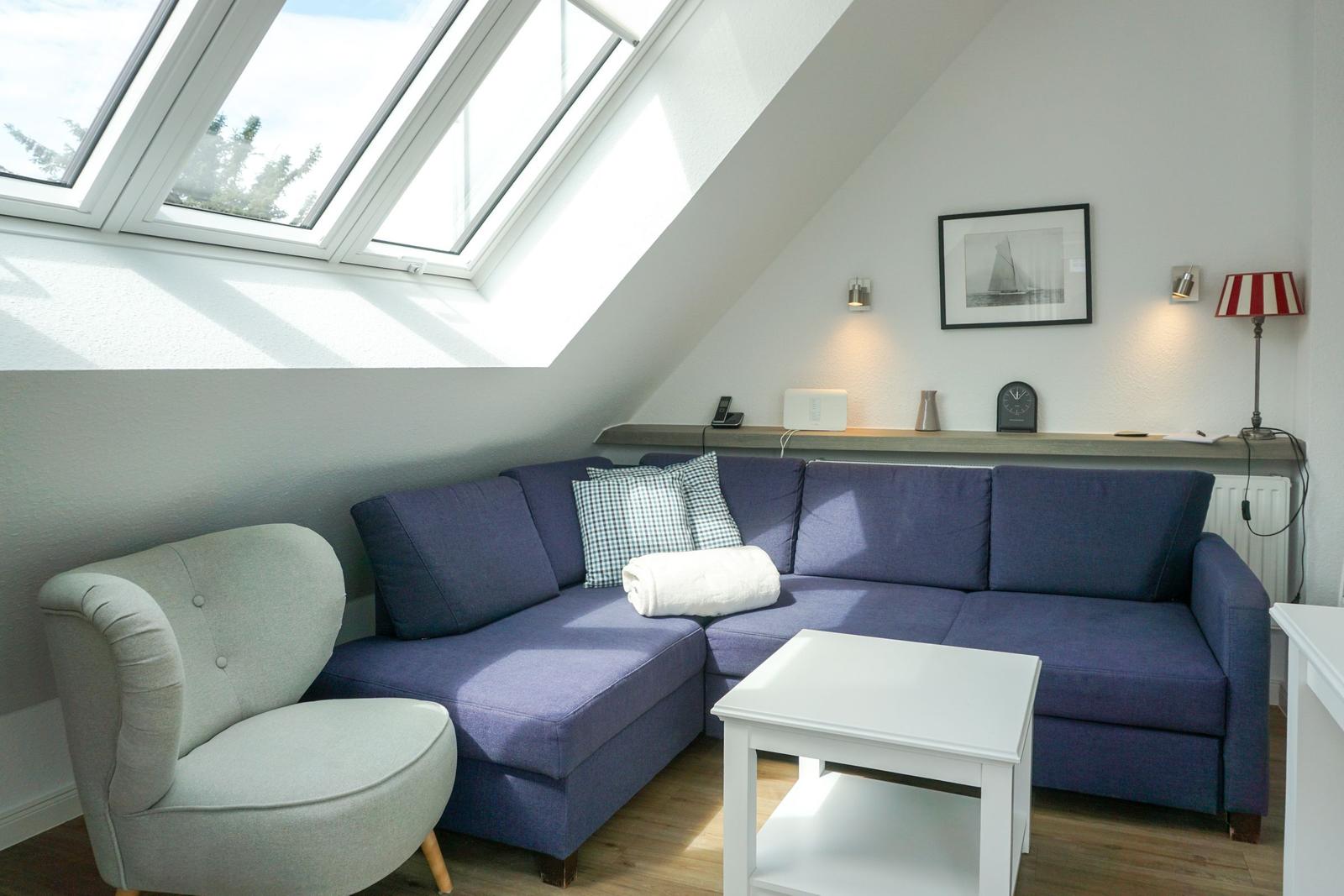 Living room with skylights, blue sofa, and gray armchair.