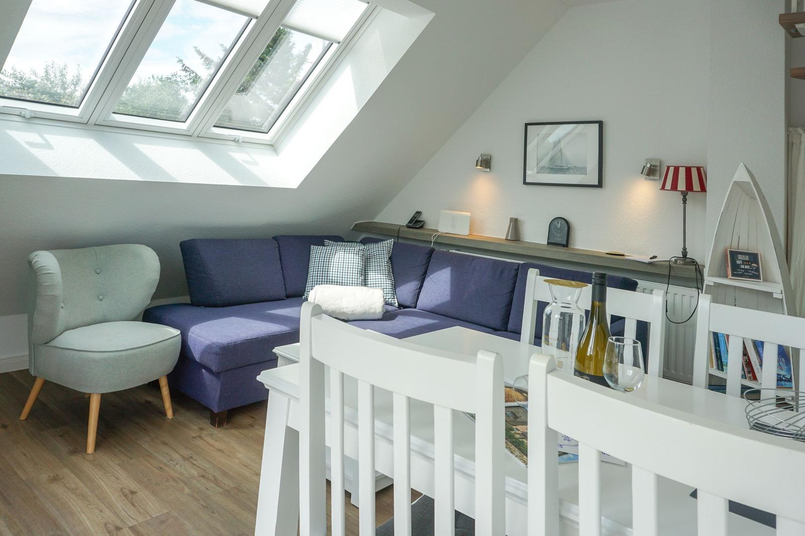 Living and dining area with sofa, chair, and skylight.
