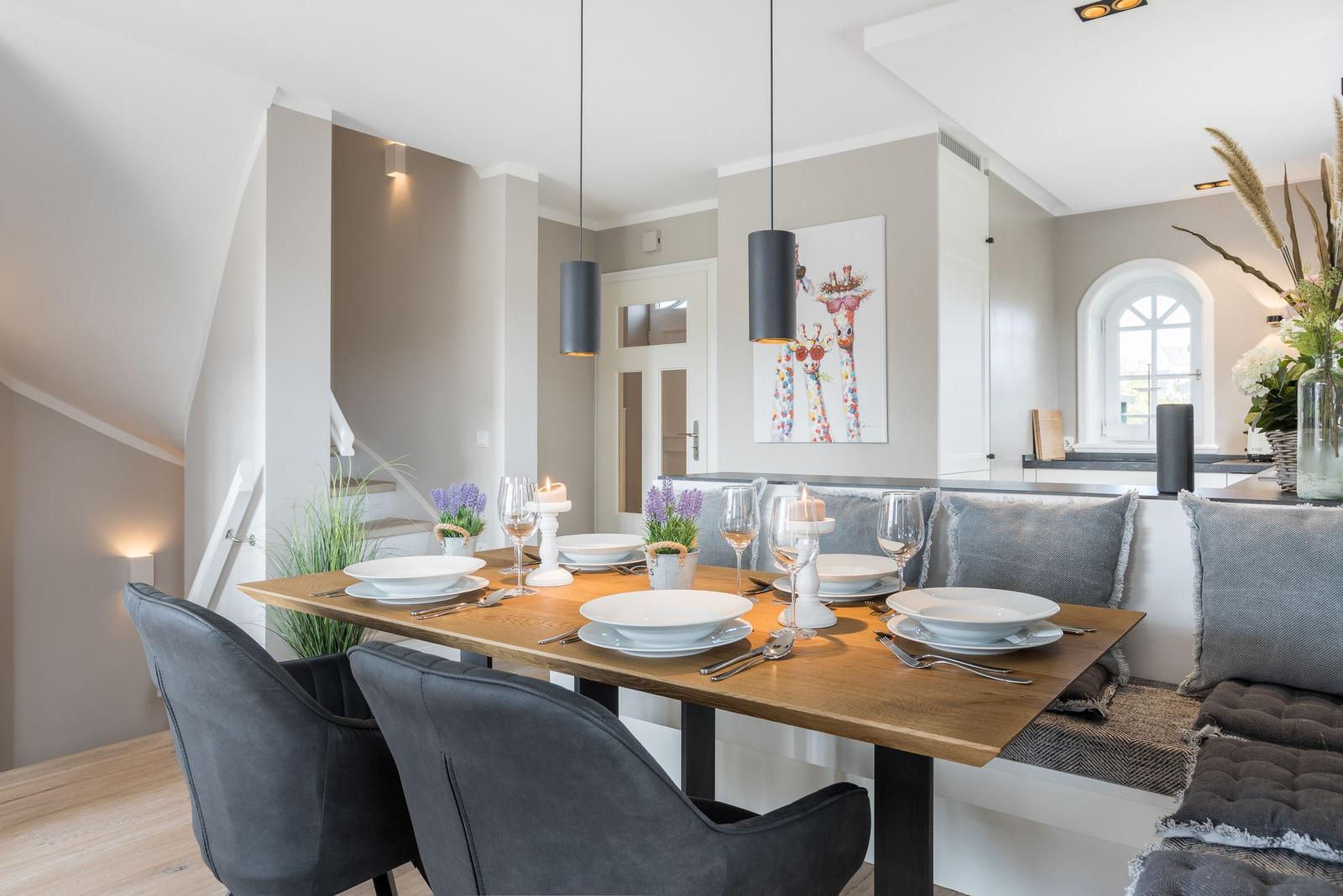 Esstisch mit sechs Stühlen und Sitzbank, Wandbild mit Giraffenmotiv, moderne Pendelleuchten.