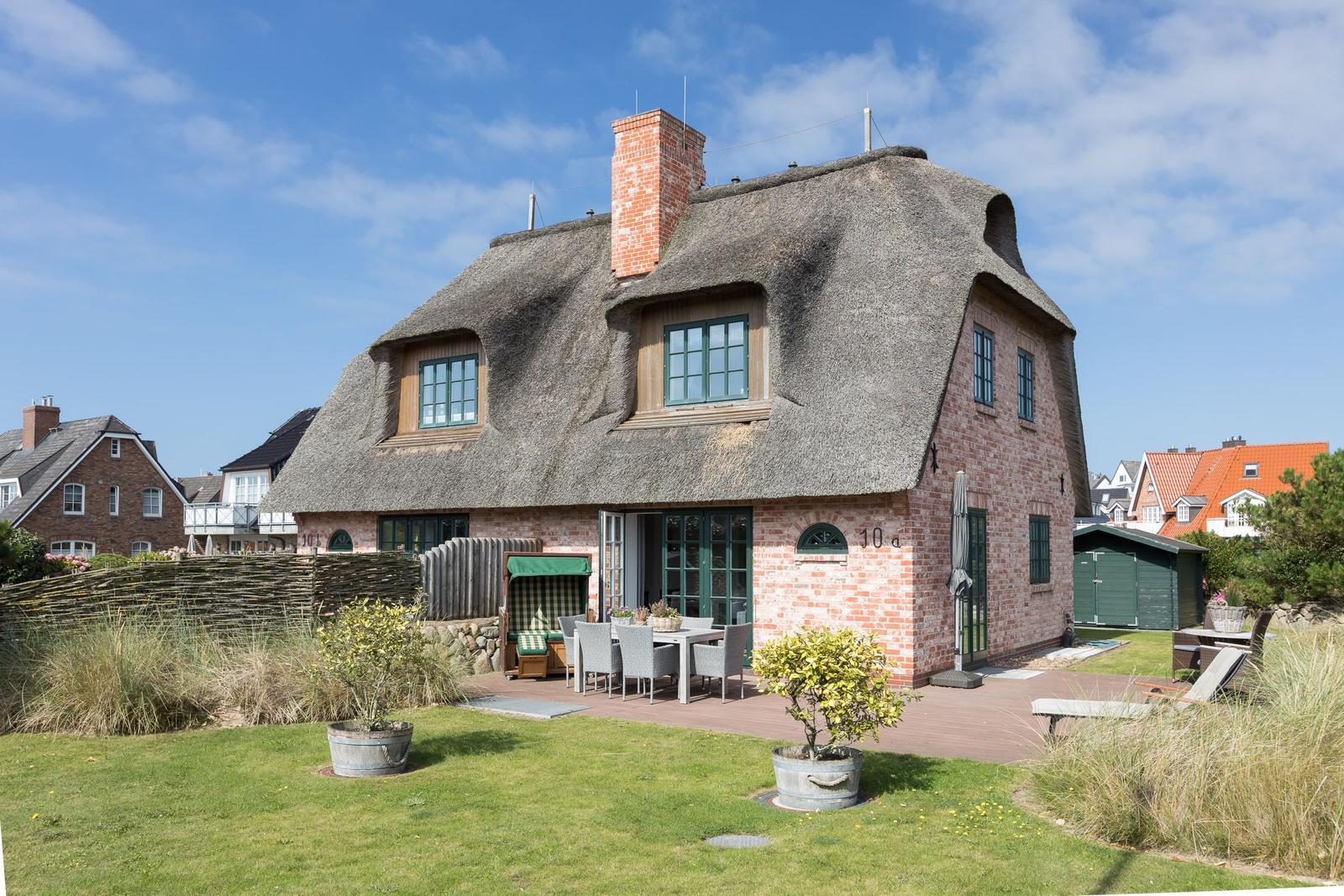 Traditionelles Haus mit Strohdach und Terrasse im Garten